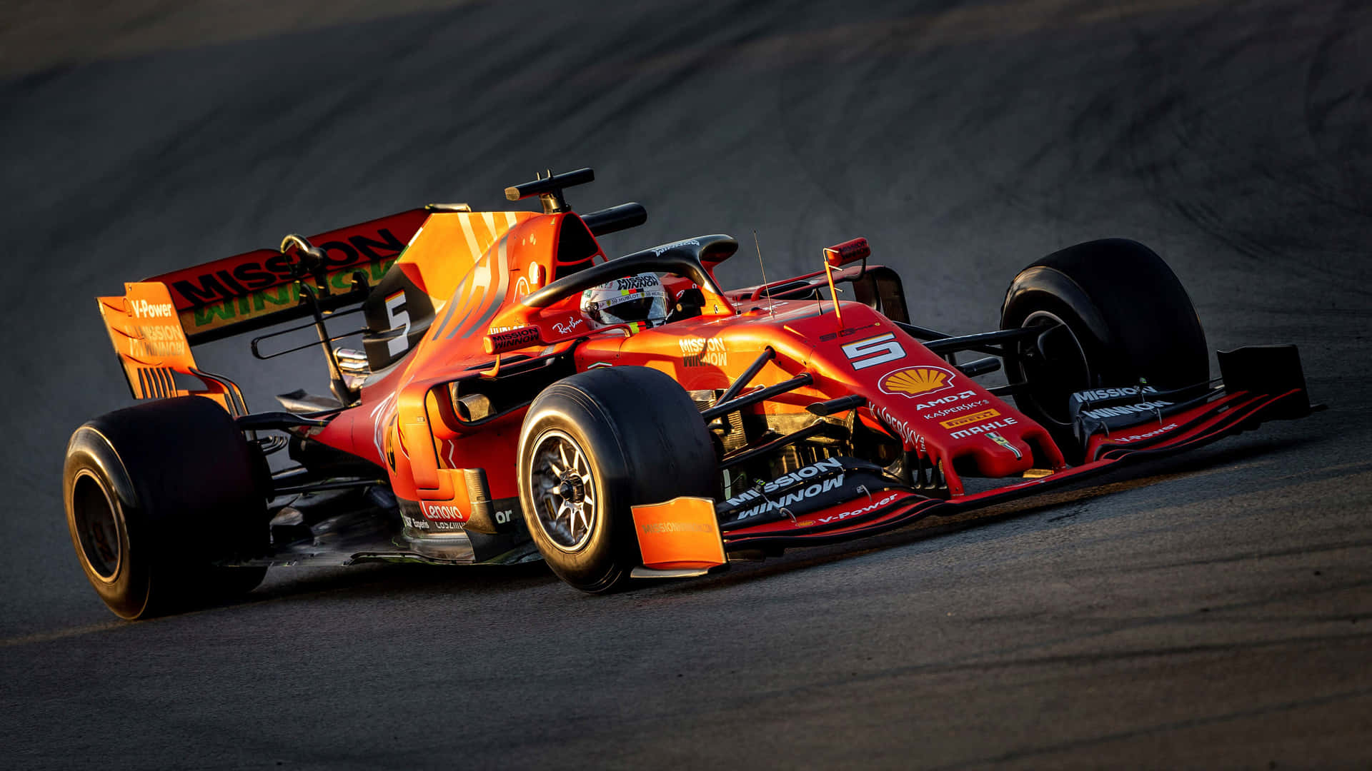 Racing 桌布 壁紙 — 一輛紅色和橙色的F1賽車，號碼5，在金色日落光線下的賽道上奔馳。