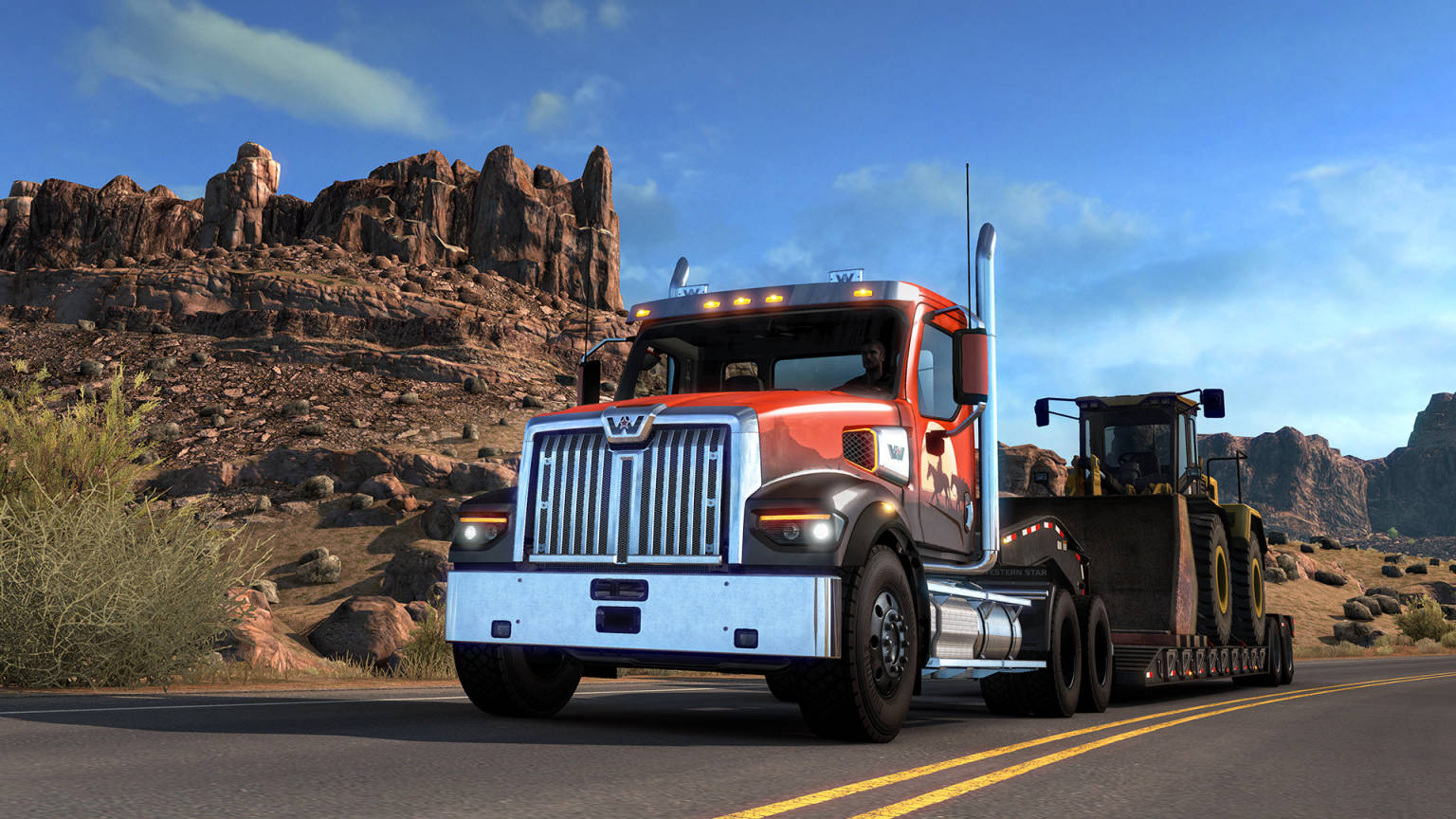 American Truck Simulator 桌布 壁紙 — 一輛紅色和銀色的半掛卡車拖著一輛黃色推土機，在晴朗藍天下沿著兩旁崎嶇岩石的沙漠高速公路行駛。