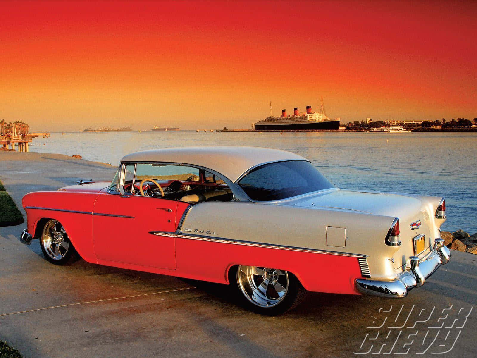 chevy 桌布 壁紙 — 一輛紅色和銀色的經典雪佛蘭Bel Air在日落時停泊在水邊，遠處有一艘遊輪。