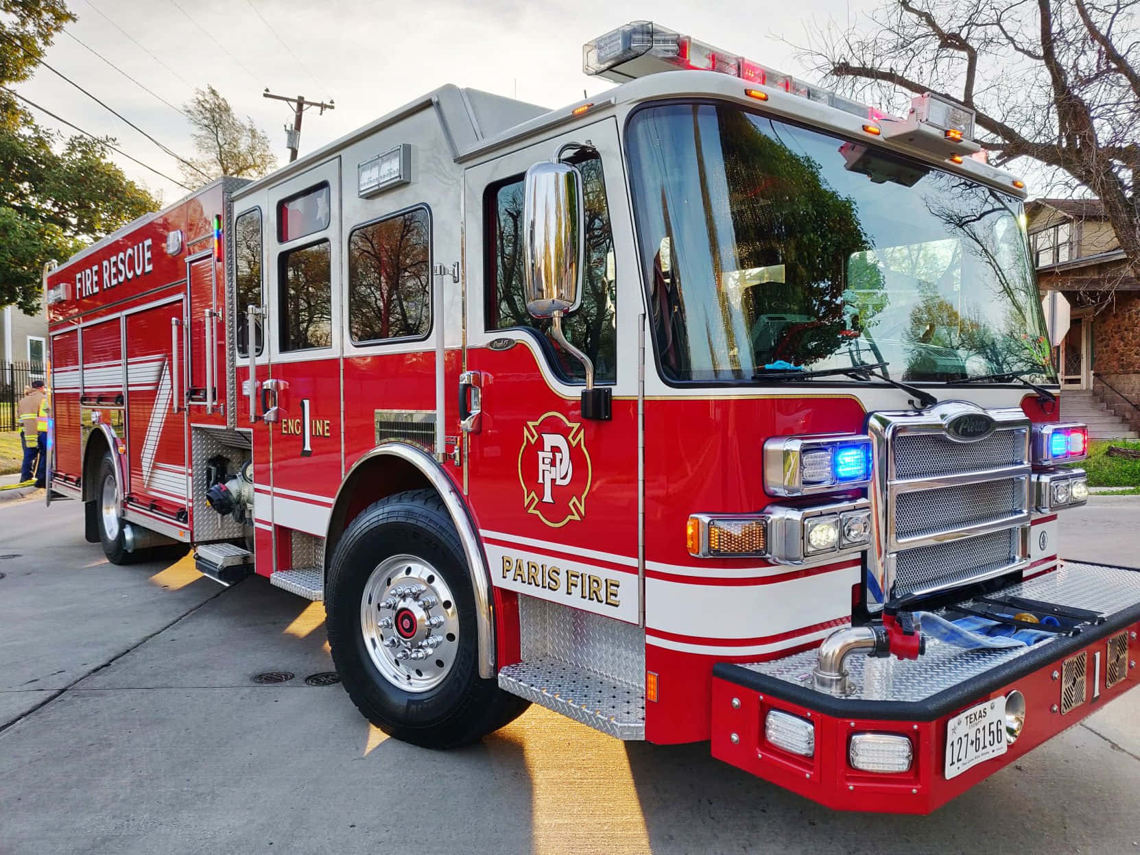 Fire Truck 桌布 壁紙 — 一輛紅色巴黎消防局引擎車停泊在郊區街道上，周圍有光禿禿的樹木和晴朗的天空。