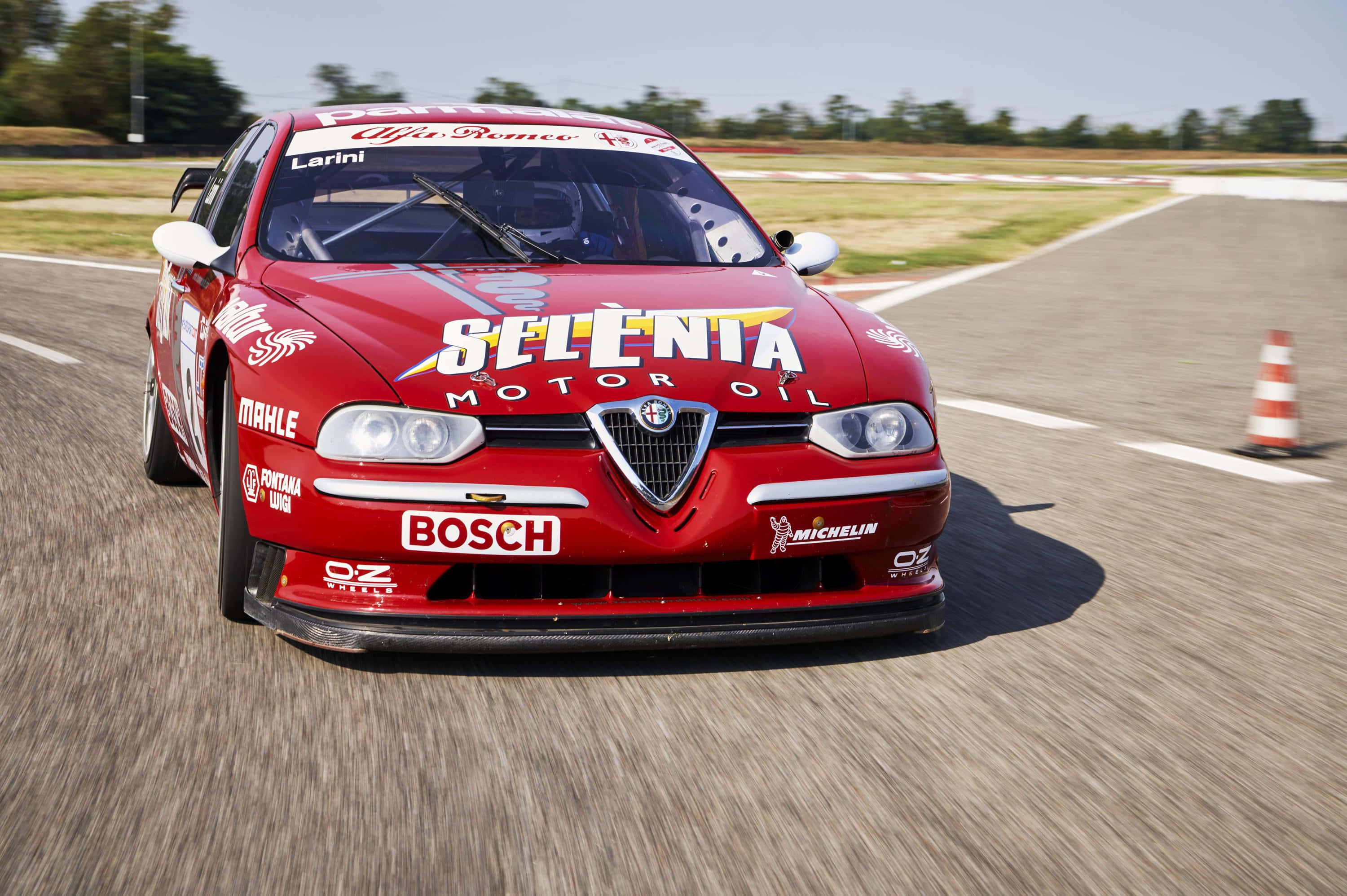 Alfa Romeo 156 桌布 壁紙 — 一輛紅色愛快羅密歐賽車在陽光明媚的賽道上疾馳，動態模糊效果凸顯其速度。