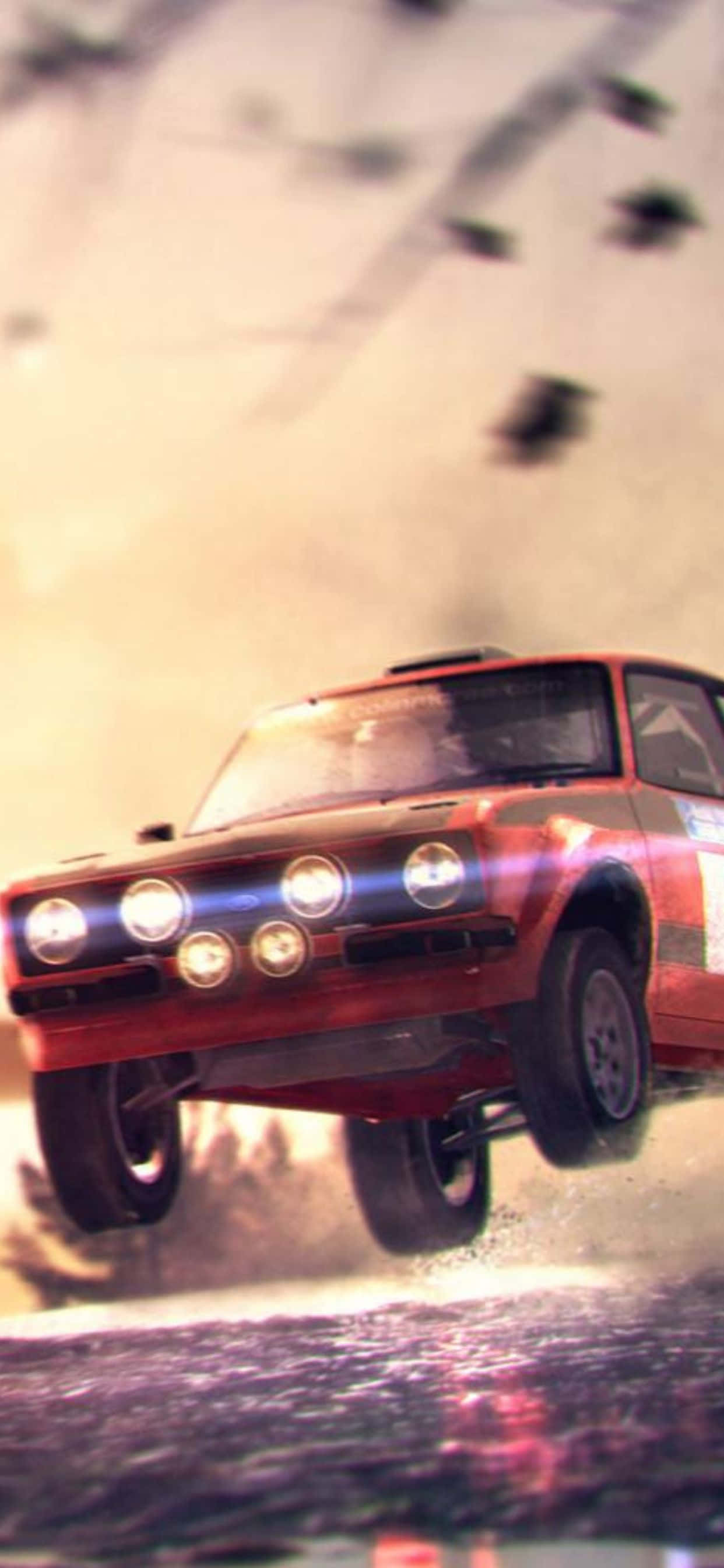 iPhone Xs Max Dirt 3 桌布 壁紙 — 一輛紅色拉力賽車在泥濘地形上飛躍，車頭燈照亮，天空朦朧。
