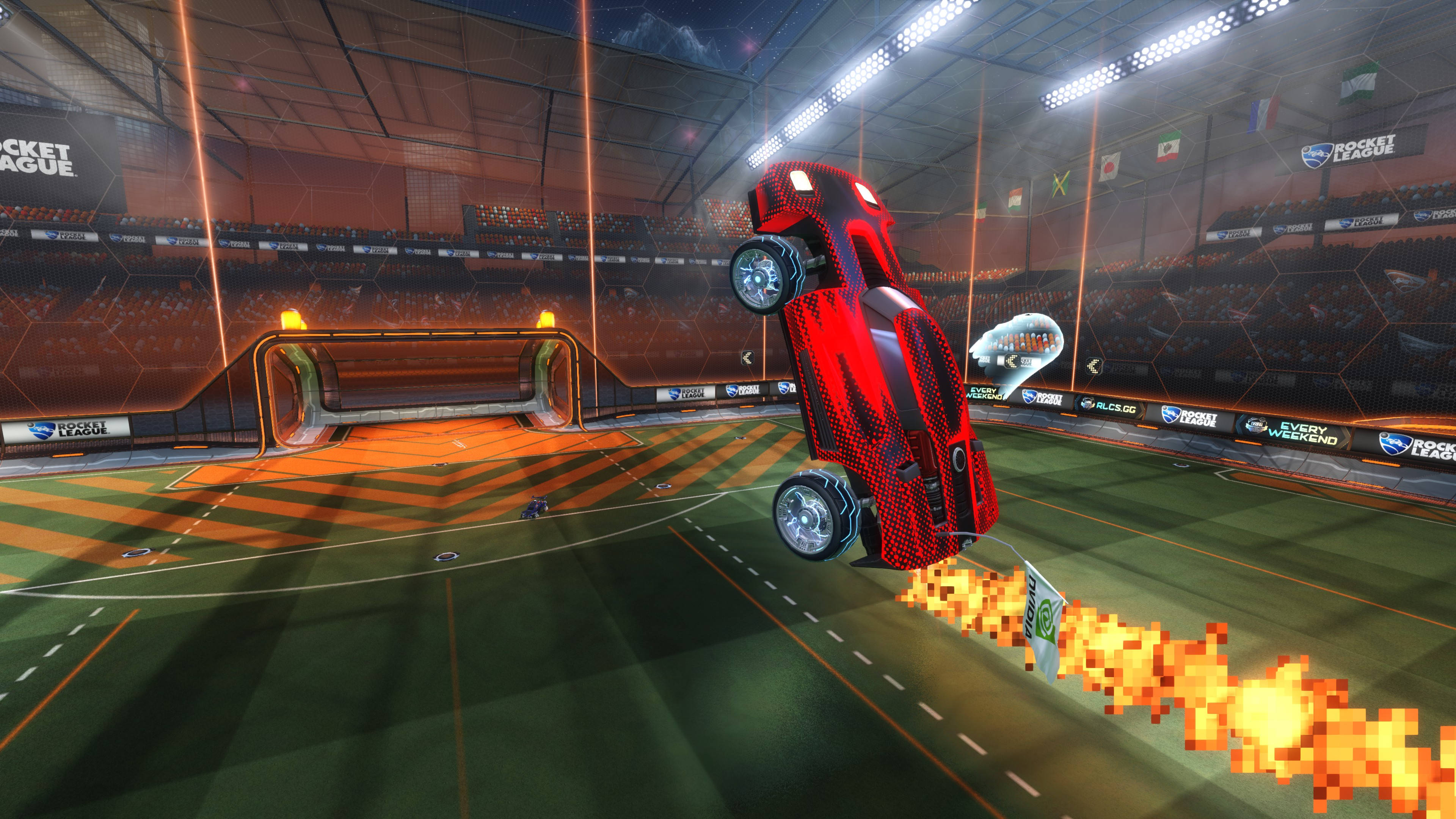 4K Rocket League 桌布 壁紙 — 一輛紅色汽車在光線明亮的室內競技場中，於一場Rocket League比賽期間在空中翻轉，身後帶有像素化火焰。