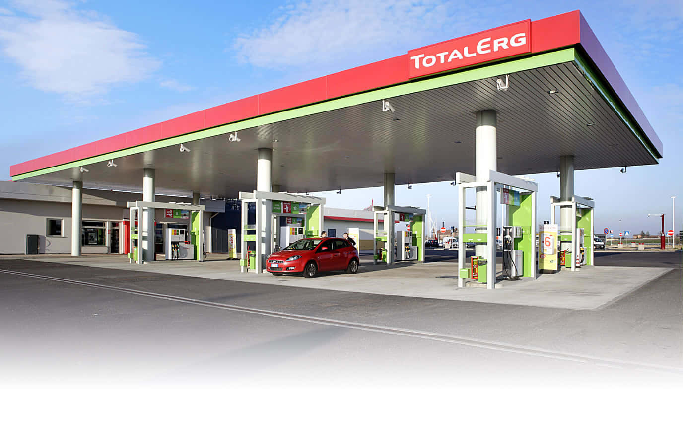 Petrol Station 桌布 壁紙 — 一輛紅色汽車在晴朗藍天下，於現代化的TotalErg加油站天篷下加油，天篷帶有綠色和紅色點綴。