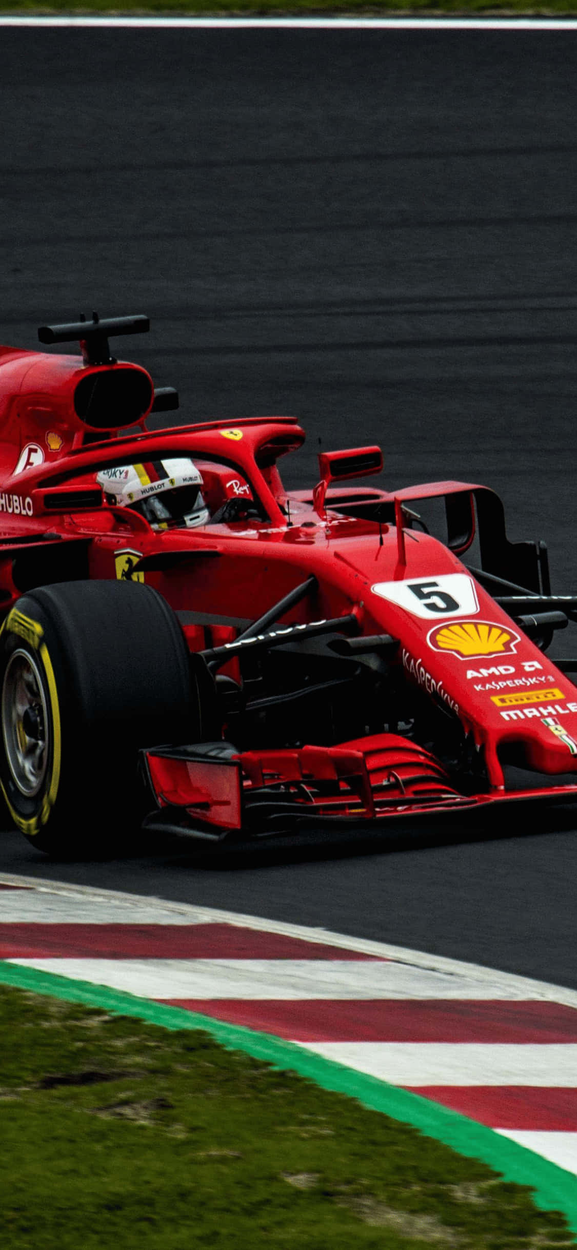 F1 2018 桌布 壁紙 — 一輛紅色法拉利F1賽車，車號5，在賽道上奔馳，賽道兩旁是綠色草地和紅白相間的賽道邊緣。