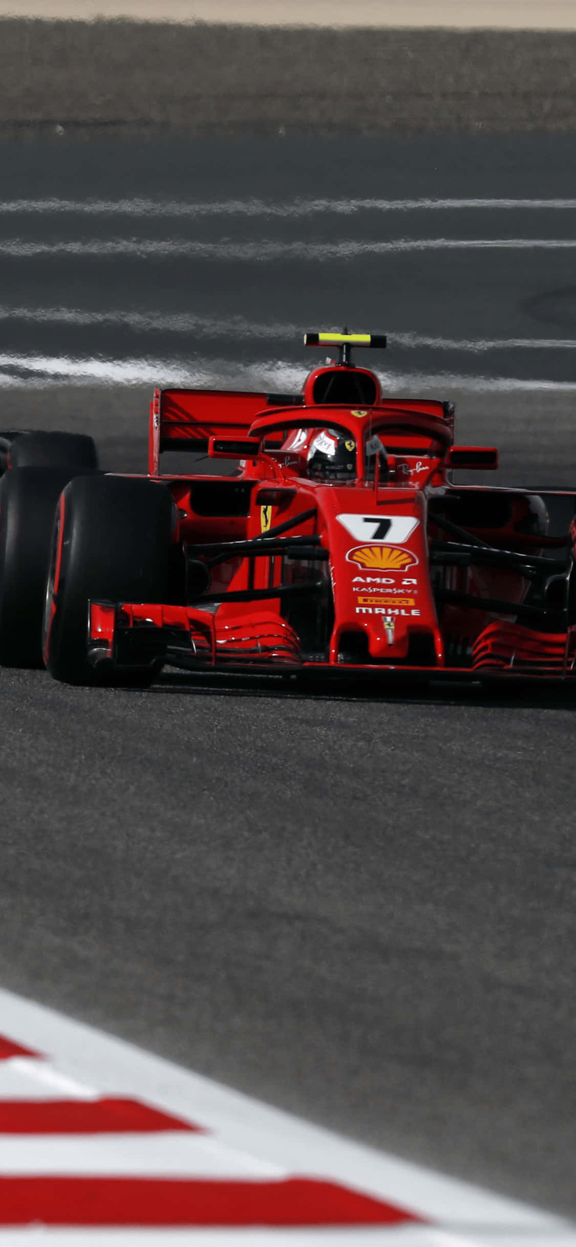 F1 2018 桌布 壁紙 — 一輛紅色法拉利F1賽車，車號7，在帶有白色路緣和模糊動感的賽道上奔馳。