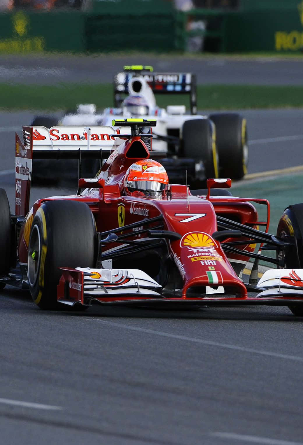 F1 2016 桌布 壁紙 — 一輛紅色法拉利一級方程式賽車，號碼7，在濕滑賽道上緊跟在一輛白色賽車後面。
