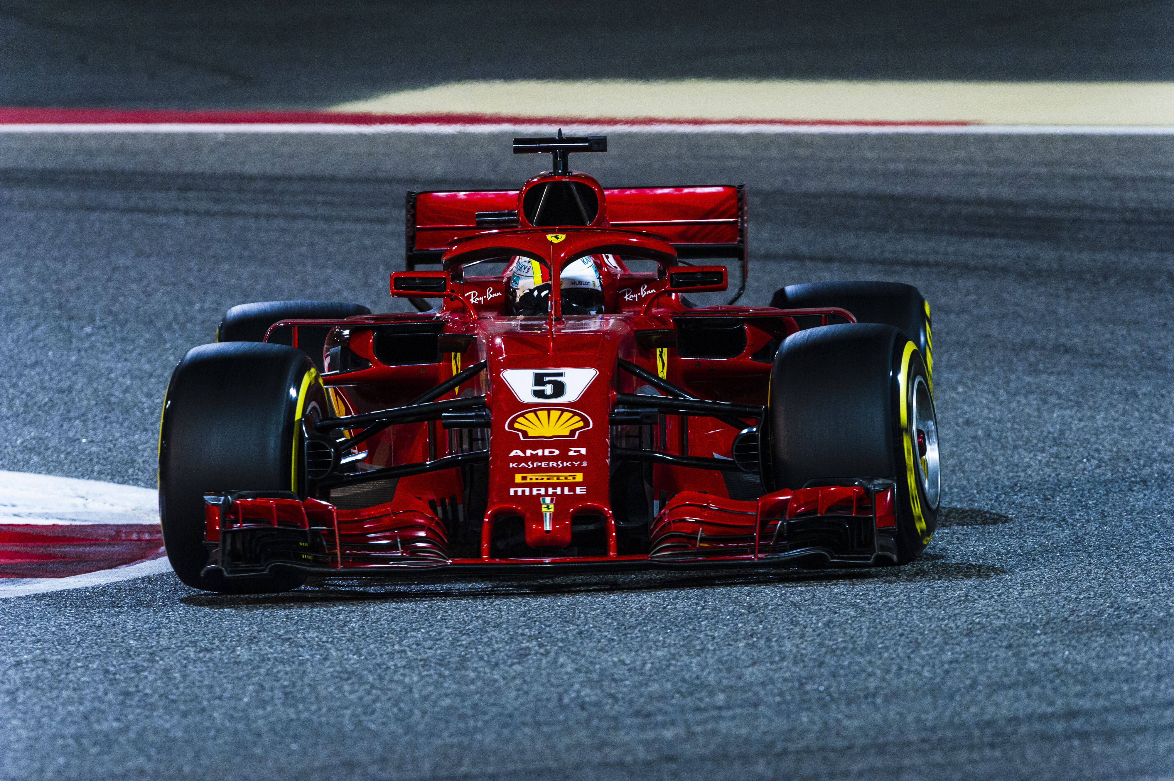 ferrari f1 2018 桌布 壁紙 — 一輛紅色法拉利一級方程式賽車，號碼5，在夜間濕滑賽道上奔馳，車頭燈閃爍。