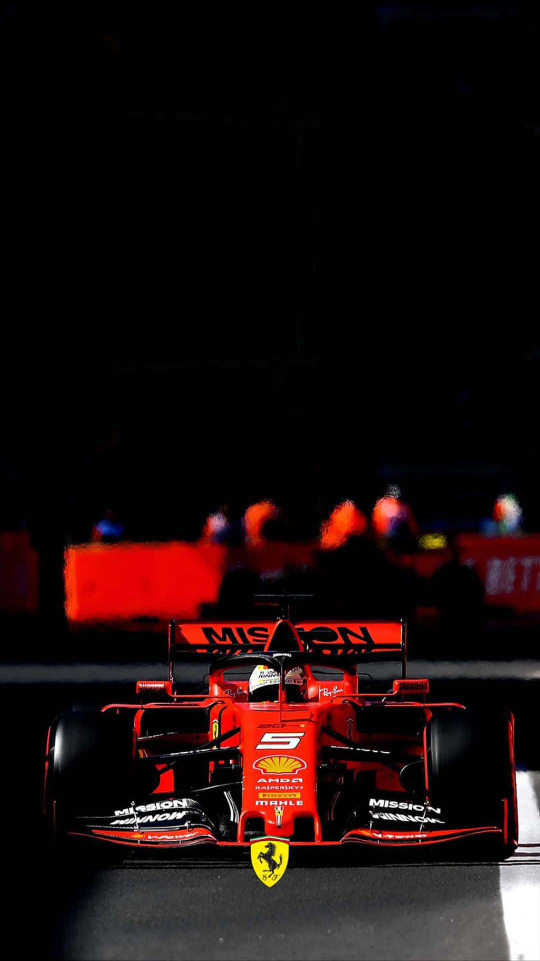 Ferrari iPhone 桌布 壁紙 — 一輛紅色法拉利一級方程式賽車在夜間被賽道燈光照亮，背景有模糊的觀眾。