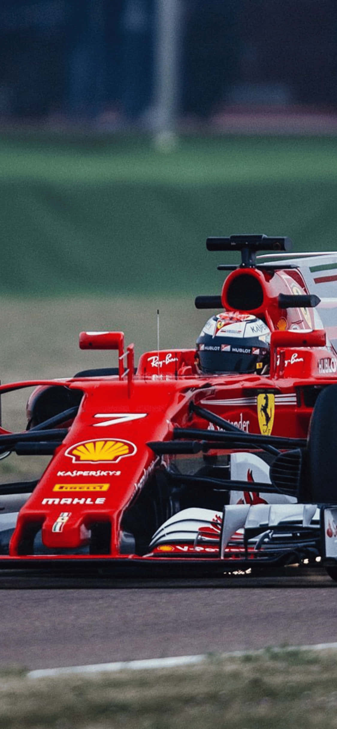 F1 2018 桌布 壁紙 — 一輛紅色法拉利一級方程式賽車在賽道上疾馳，背景是模糊的綠色草地和賽道邊的護欄。