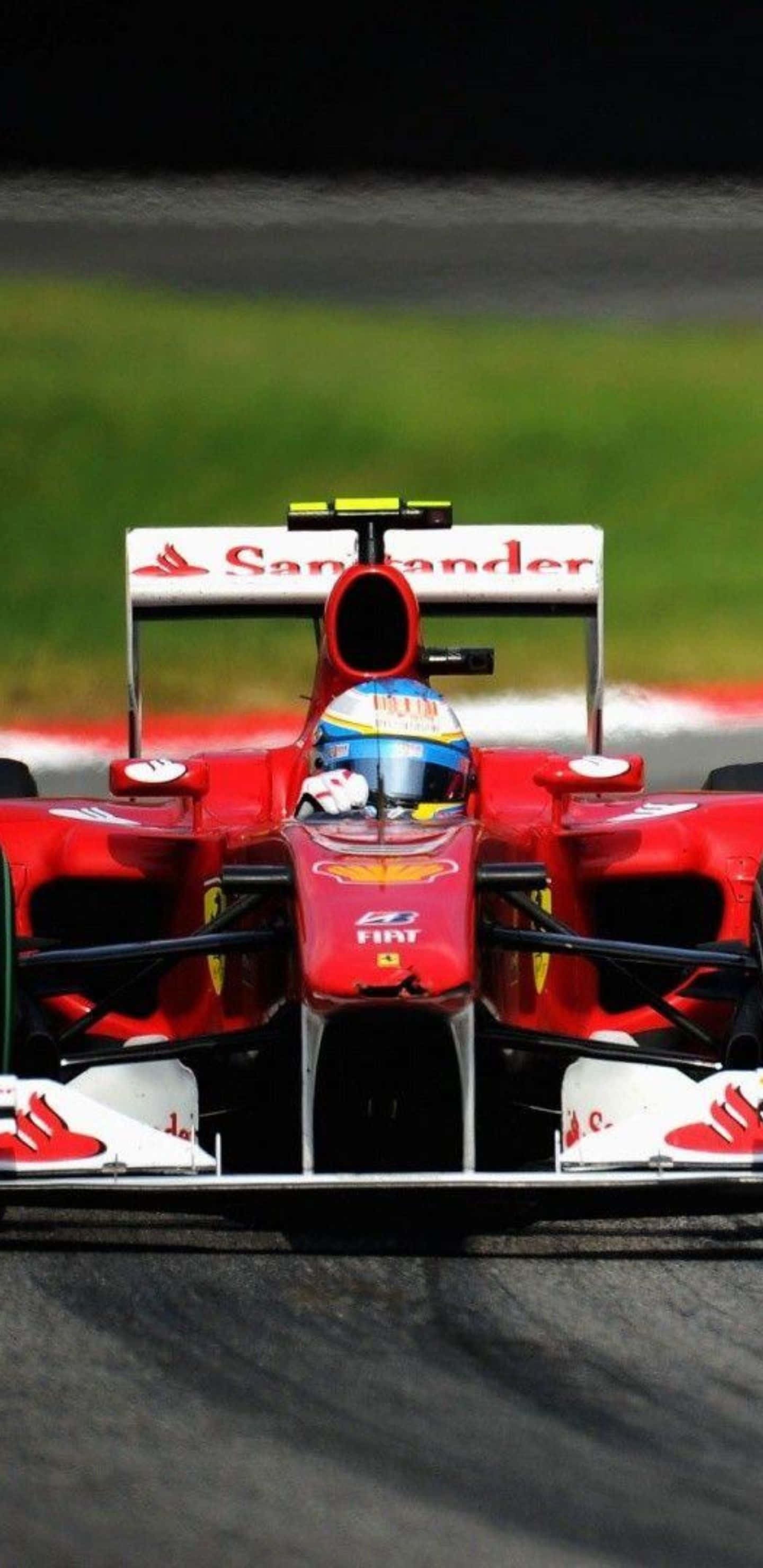 Formula 1 桌布 壁紙 — 一輛紅色法拉利一級方程式賽車在賽道上奔馳，背景是模糊的綠色草地和紅白相間的賽道邊緣。