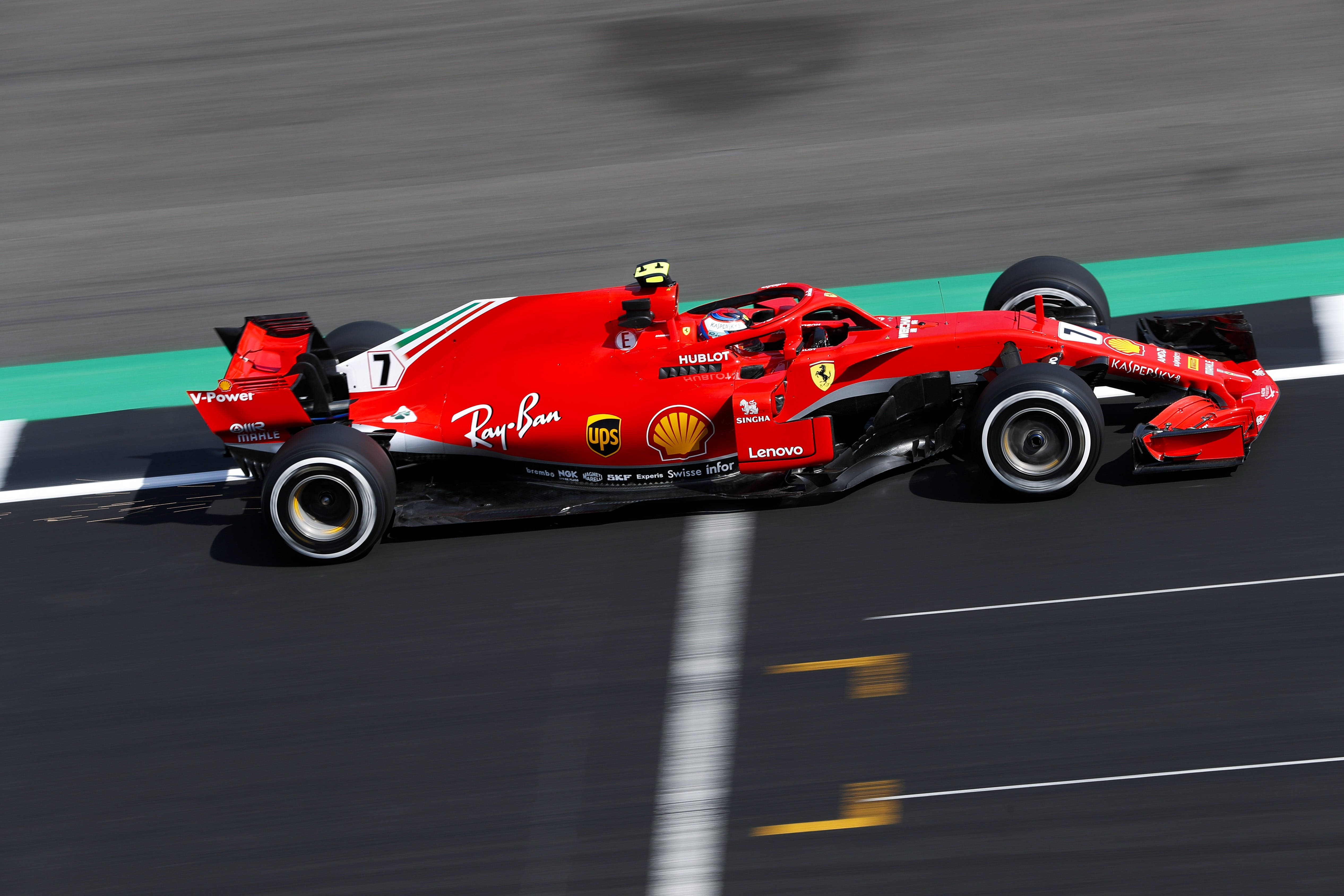 ferrari f1 2018 桌布 壁紙 — 一輛紅色法拉利一級方程式賽車在賽道上疾馳，瀝青路面和綠色路緣帶呈現動態模糊效果。