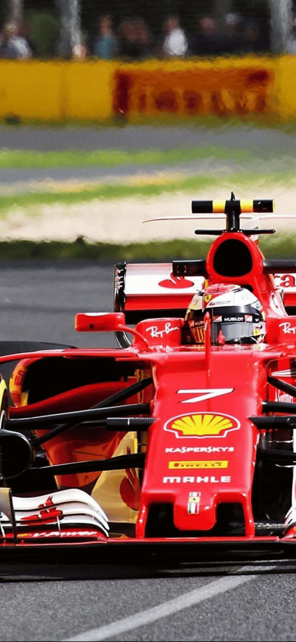 F1 2018 桌布 壁紙 — 一輛紅色法拉利一級方程式賽車在賽道上疾馳，背景有模糊的觀眾和綠色草地。