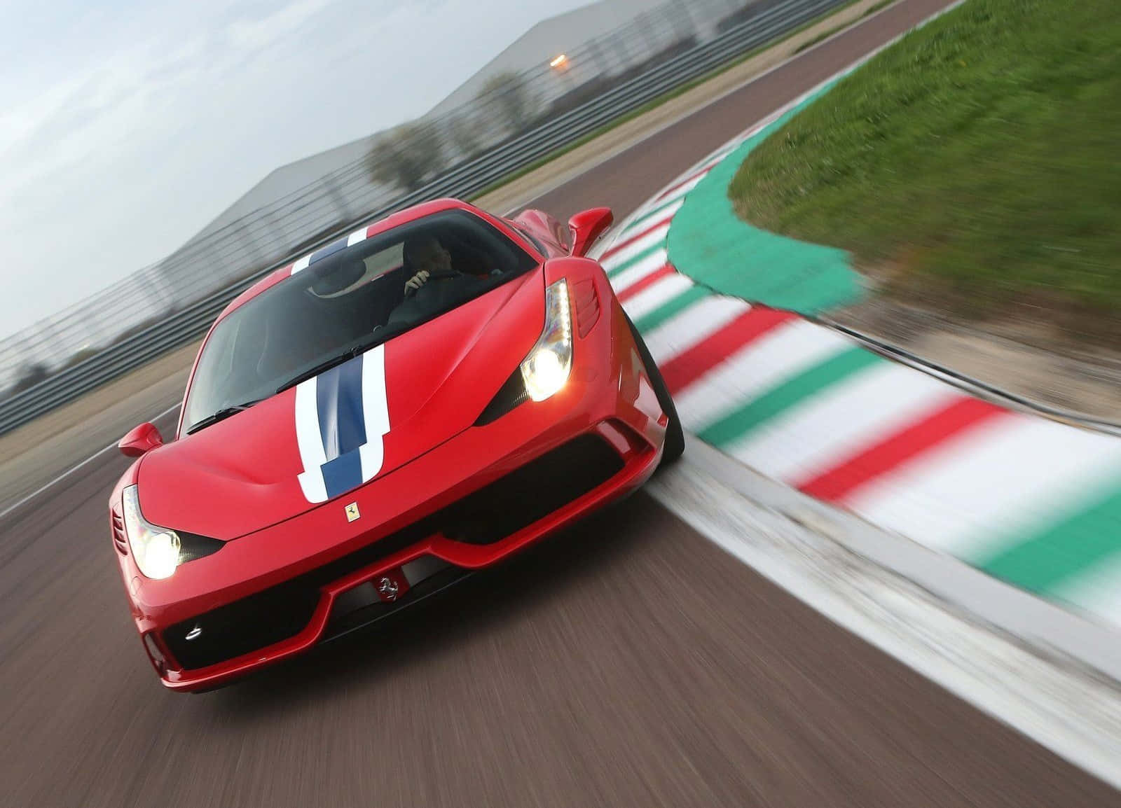 Ferrari 458 Speciale 桌布 壁紙 — 一輛紅色法拉利在賽道彎道高速行駛，帶有動態模糊效果和義大利國旗路緣石。