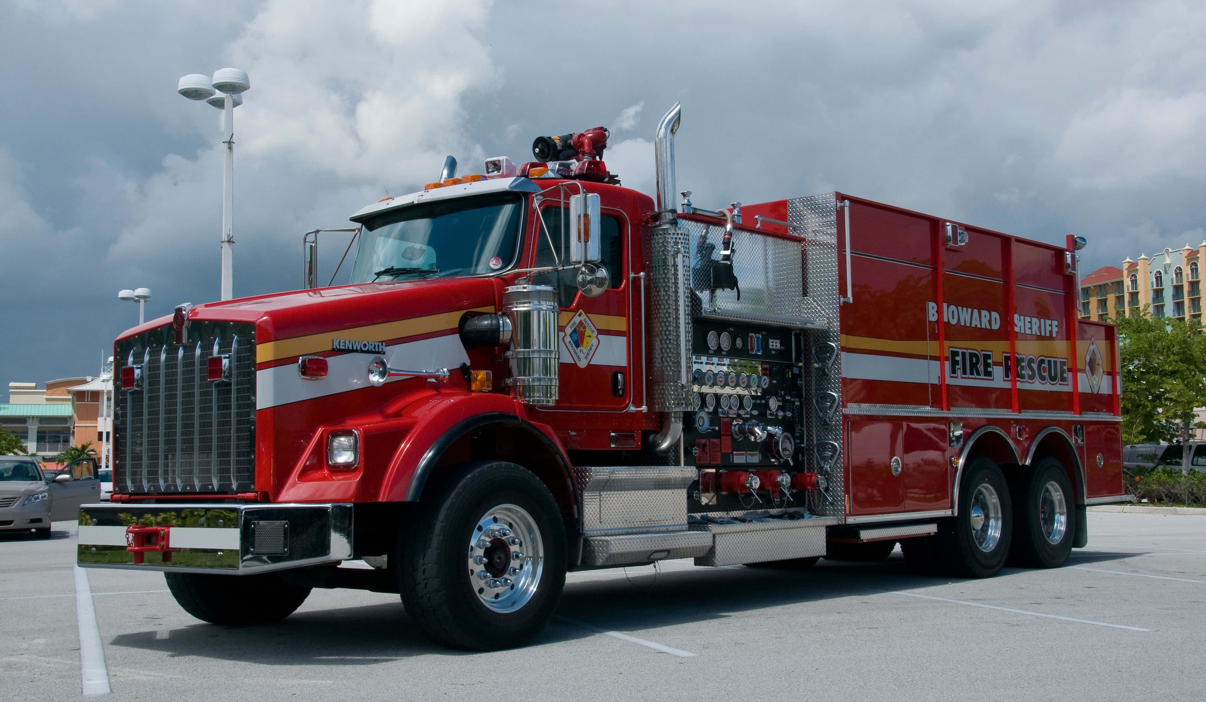 Fire Truck 桌布 壁紙 — 一輛紅色的 Broward 警長消防救護車停放在停車場，天空多雲，背景有建築物。