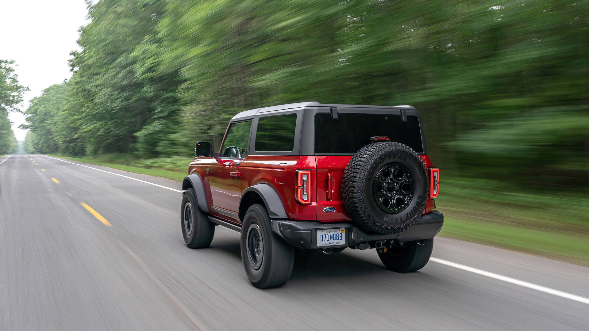 Ford Bronco 桌布 壁紙 — 一輛紅色福特Bronco SUV在樹木成行的道路上疾馳，動態模糊傳達出快速移動的感覺。