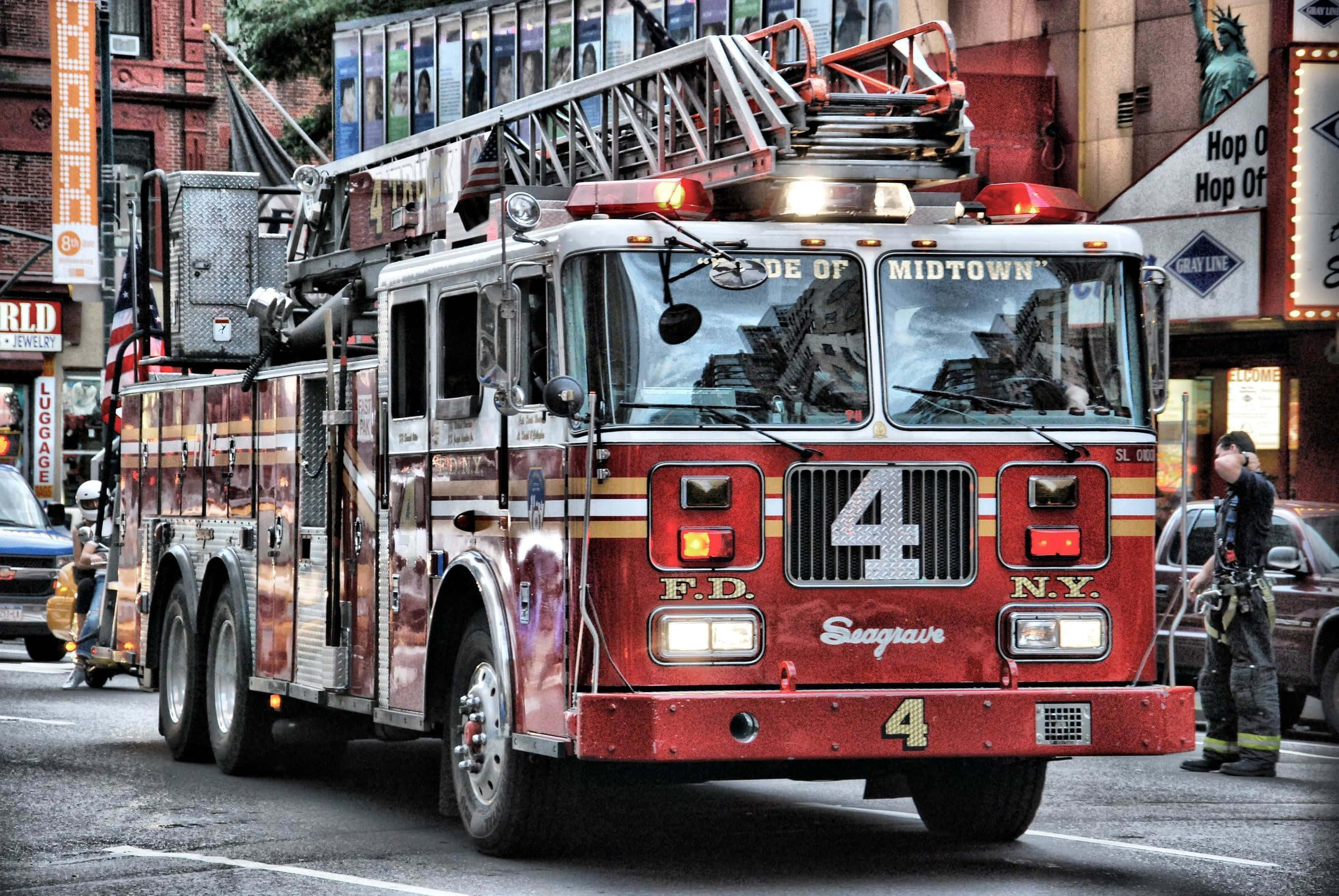 Fire Department 桌布 壁紙 — 一輛紅色紐約市消防車，梯子伸展，停放在消防員附近的市區街道上。