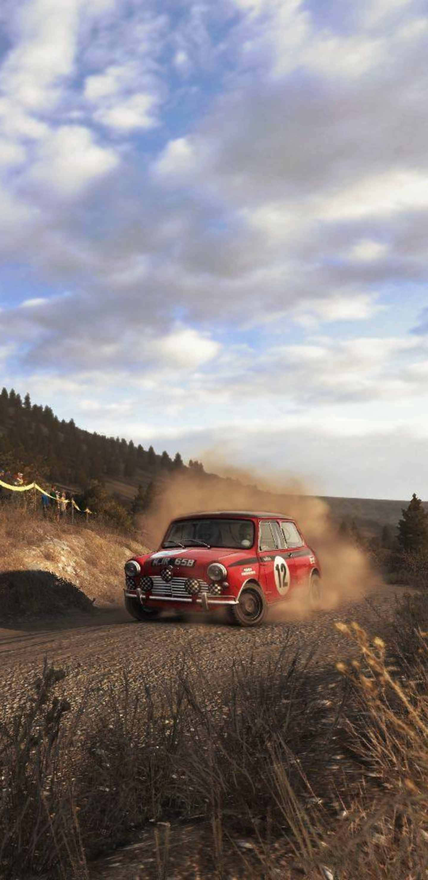 Android Dirt Rally 桌布 壁紙 — 一輛紅色經典拉力賽車在多雲天空下的丘陵景觀中，在碎石路上揚起塵土。