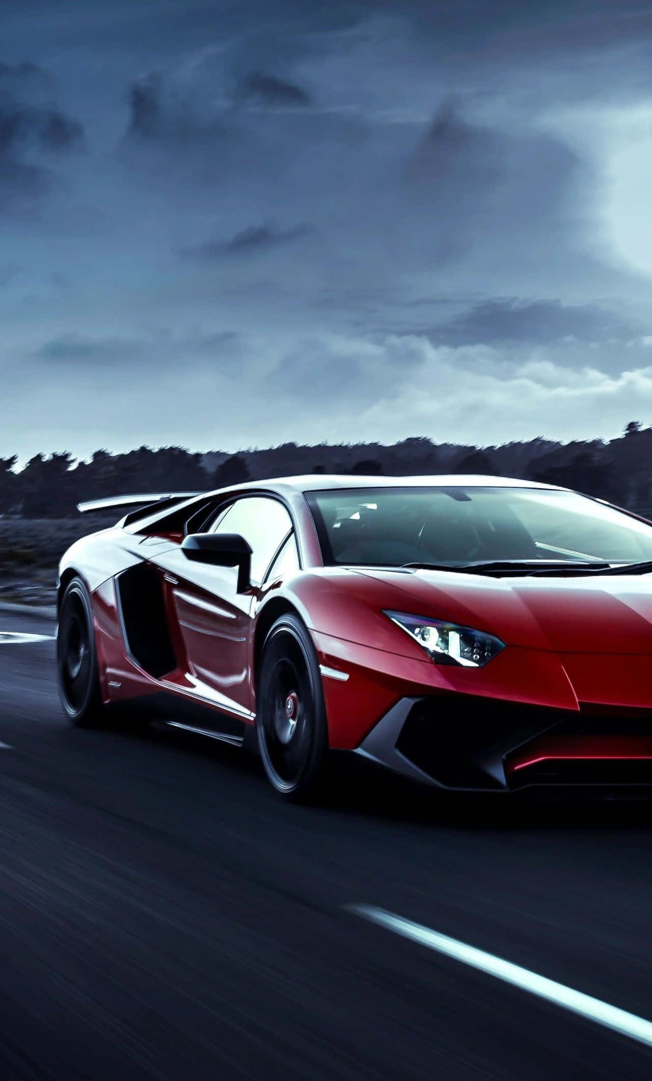Lamborghini Phone 桌布 壁紙 — 一輛紅色藍寶堅尼Aventador在暴風雨黃昏的天空下，沿著濕滑的道路疾馳，帶有模糊的動態線條。