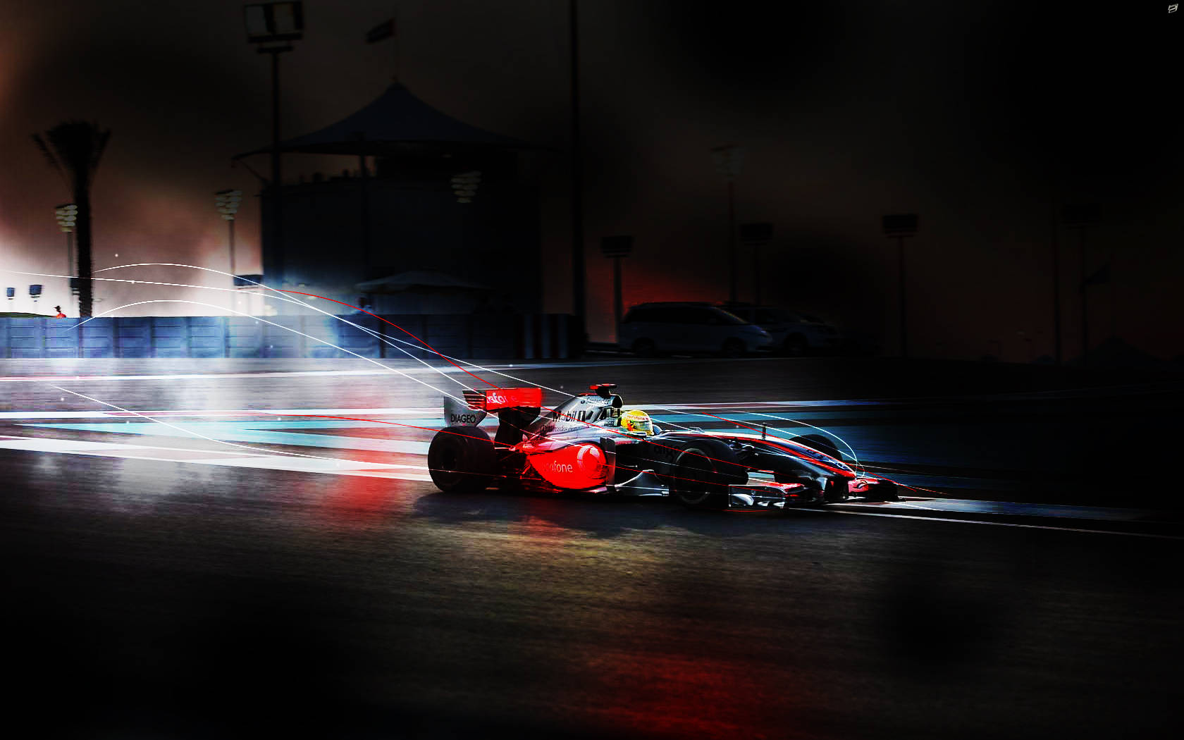 Formula 1 Desktop 桌布 壁紙 — 一輛紅色賽車在夜間濕滑的賽道上高速行駛，身後留下發光的燈光軌跡。