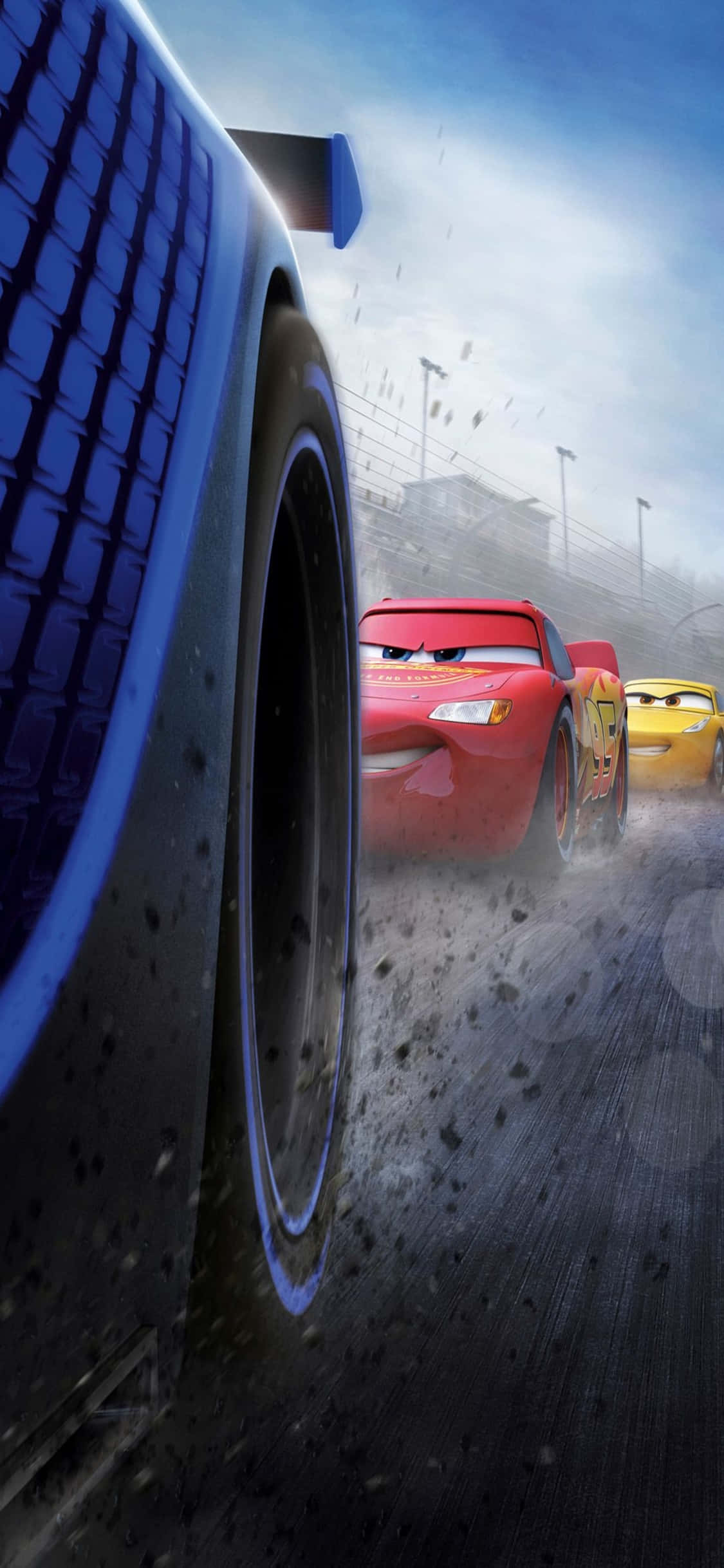 Lightning Mcqueen 桌布 壁紙 — 一輛紅色賽車帶著富有表情的眼睛，在多雲的天空下，在塵土飛揚的賽道上超越一輛藍色汽車。
