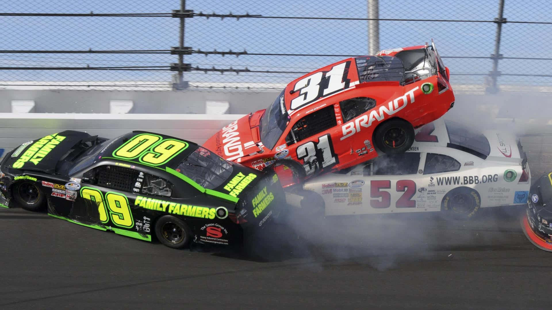 nascar 桌布 壁紙 — 一輛紅色賽車翻過一輛白色汽車，同時一輛綠色賽車在高速撞車期間在賽道上打滑。