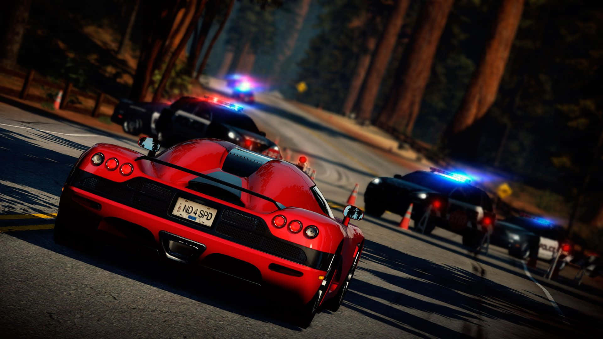 Best Need For Speed 桌布 壁紙 — 一輛紅色跑車在黃昏時分沿著森林道路疾馳，後面有閃著警燈的警車追趕。