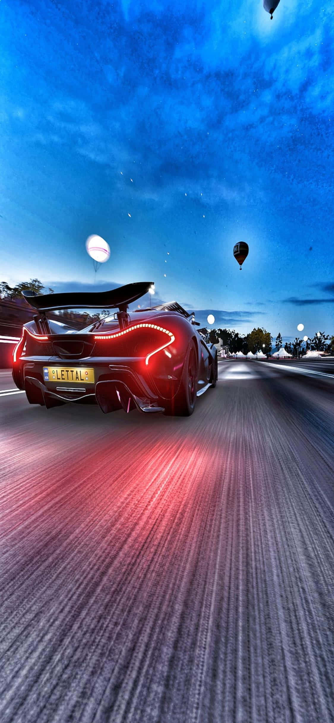 iPhone Xs Forza Horizon 4 桌布 壁紙 — 一輛紅色跑車在黃昏時分沿著道路疾馳，尾燈閃爍，熱氣球漂浮在暮色天空中。