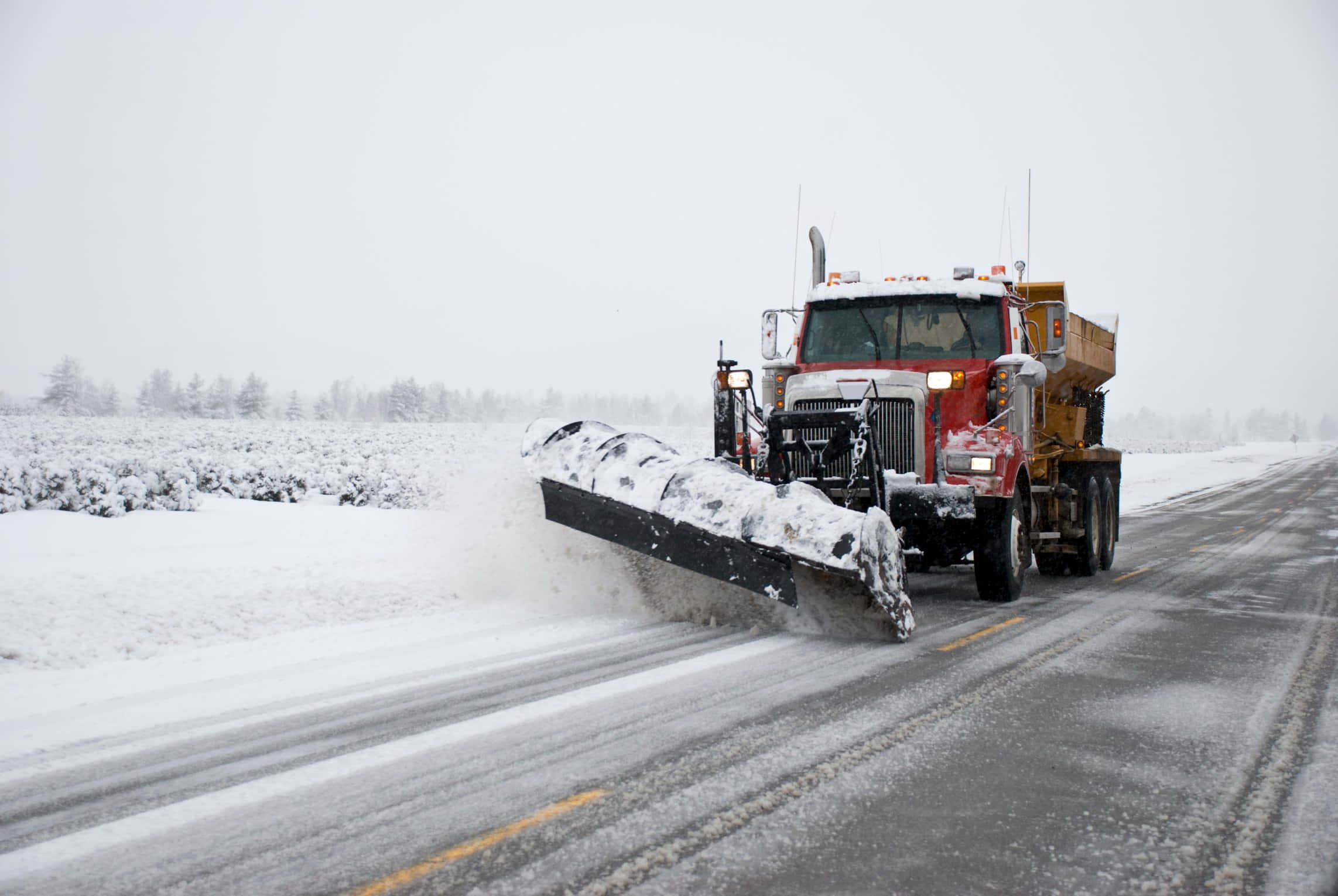 Snowplow 桌布 壁紙 — 一輛紅色除雪卡車正在清除一條穿過冬季景觀的積雪道路，背景是白雪覆蓋的樹木。