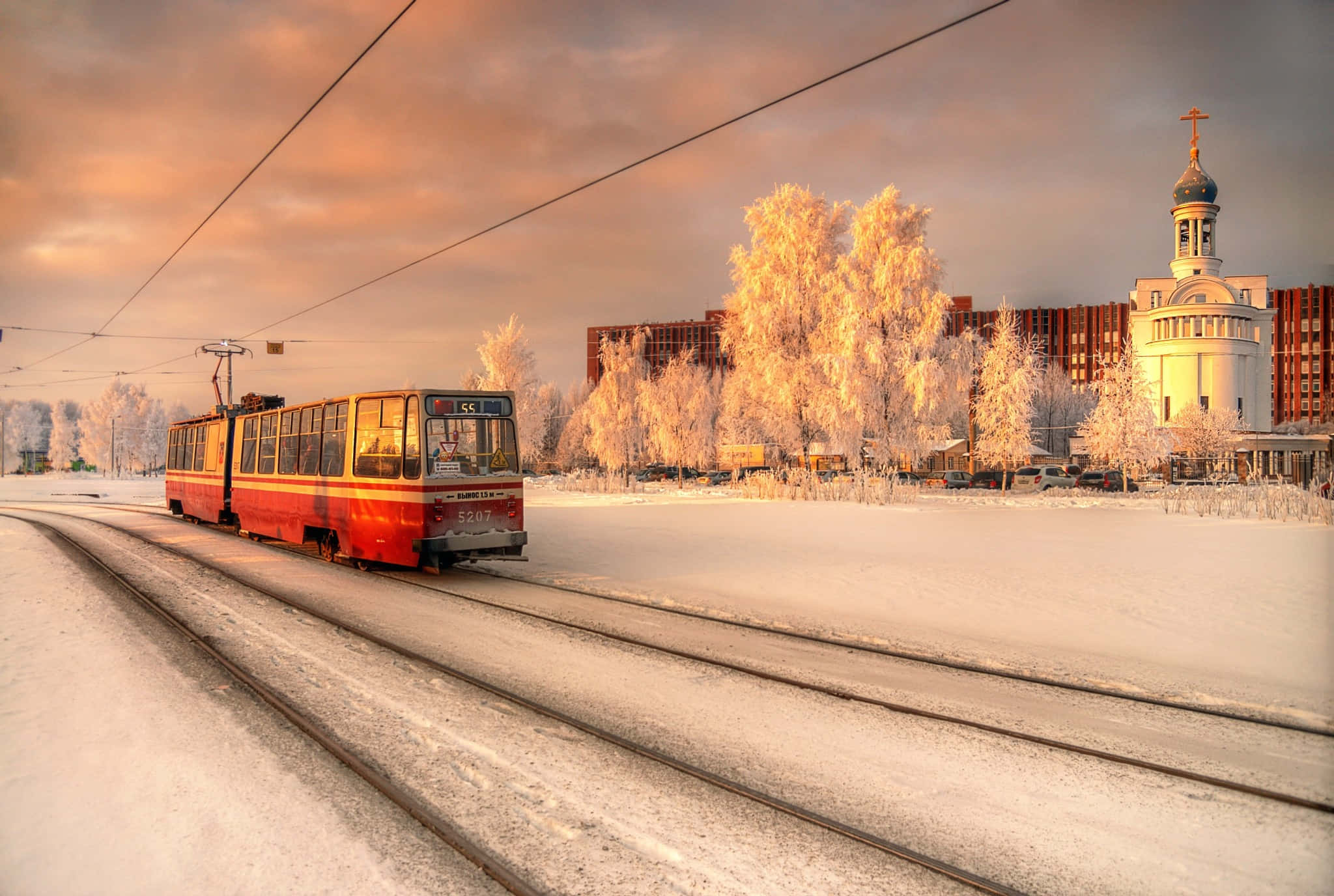 Russian 桌布 壁紙 — 一輛紅色電車在日落時分滑過白雪覆蓋的城市景觀，背景有結霜的樹木和一座教堂。