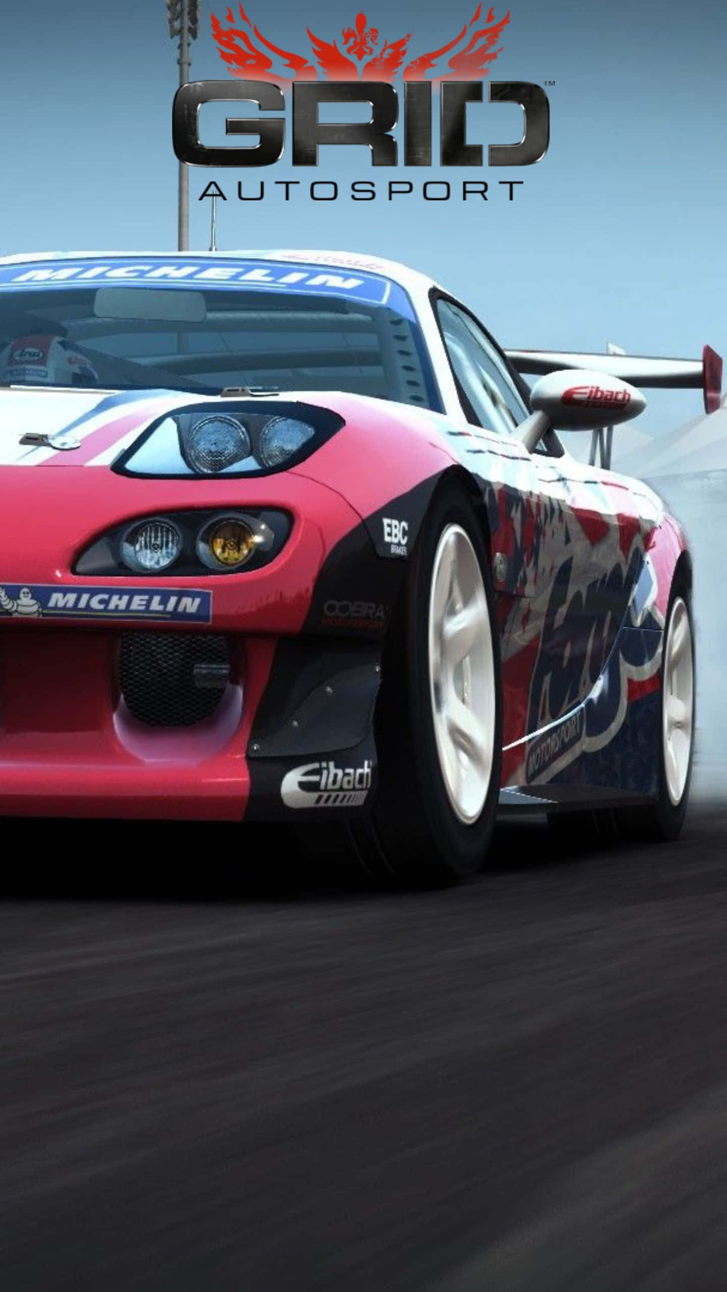 Android Grid Autosport 桌布 壁紙 — 一輛紅藍賽車在賽道上疾馳，帶有動態模糊和可見的贊助商標誌。