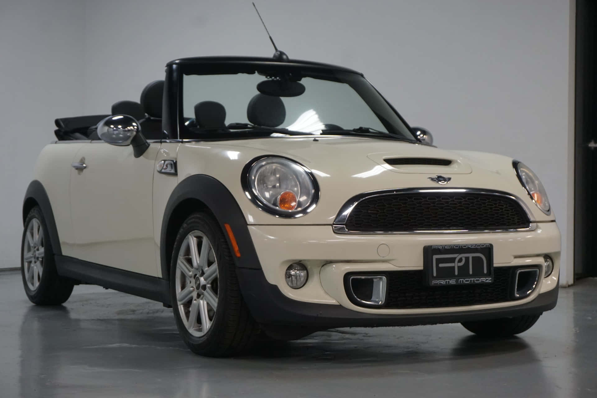 Mini Cooper S Convertible 桌布 壁紙 — 一輛純淨的奶油色Mini Cooper敞篷車，帶有黑色飾件和銀色輪圈，在明亮的攝影棚燈光下停放在室內。