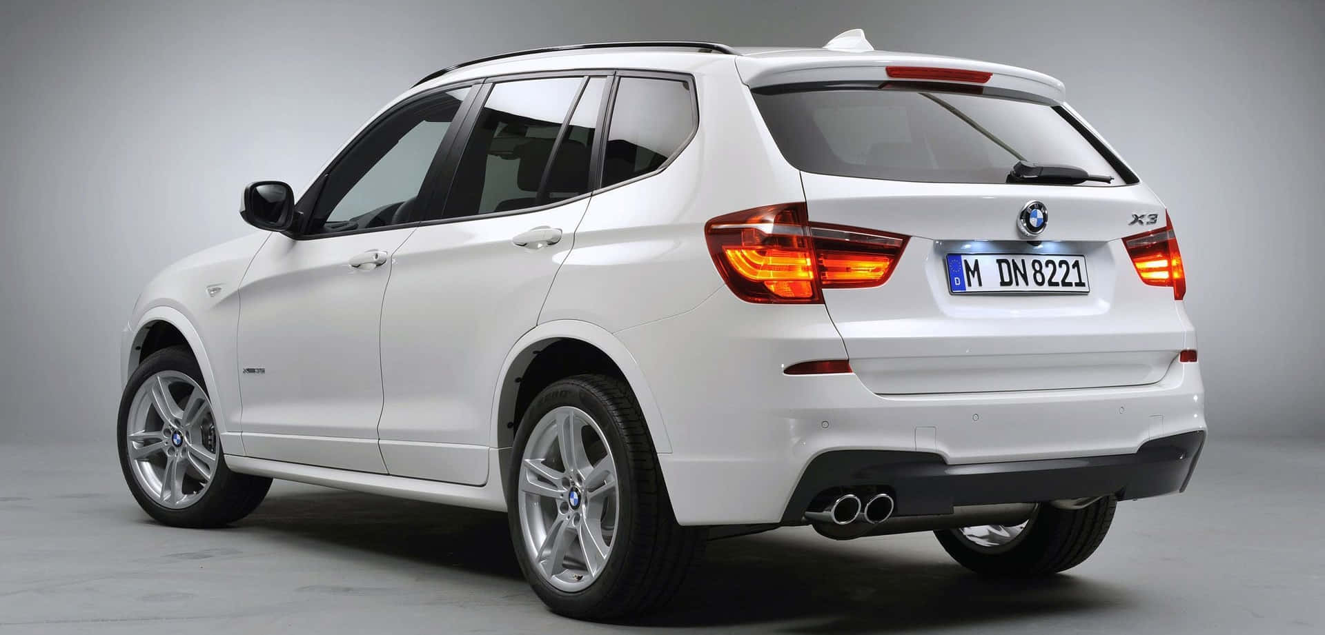 Bmw X3 桌布 壁紙 — 一輛純白色BMW X3 SUV在攝影棚中展示，尾燈亮起，雙排氣管清晰可見。