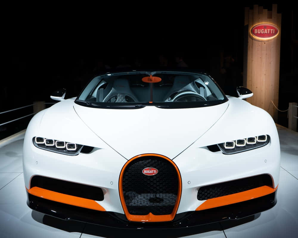 Best Bugatti 桌布 壁紙 — 一輛純白色Bugatti跑車，帶有醒目的橙色點綴，在車展的聚光燈下閃閃發光。