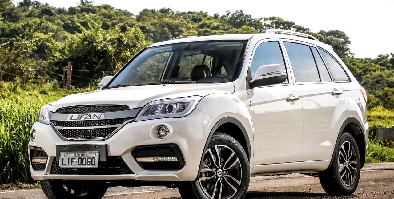 Lifan 桌布 壁紙 — 一輛純白色力帆SUV停泊在鄉村道路上，背景是茂密的綠色樹葉，在明亮的日光下。