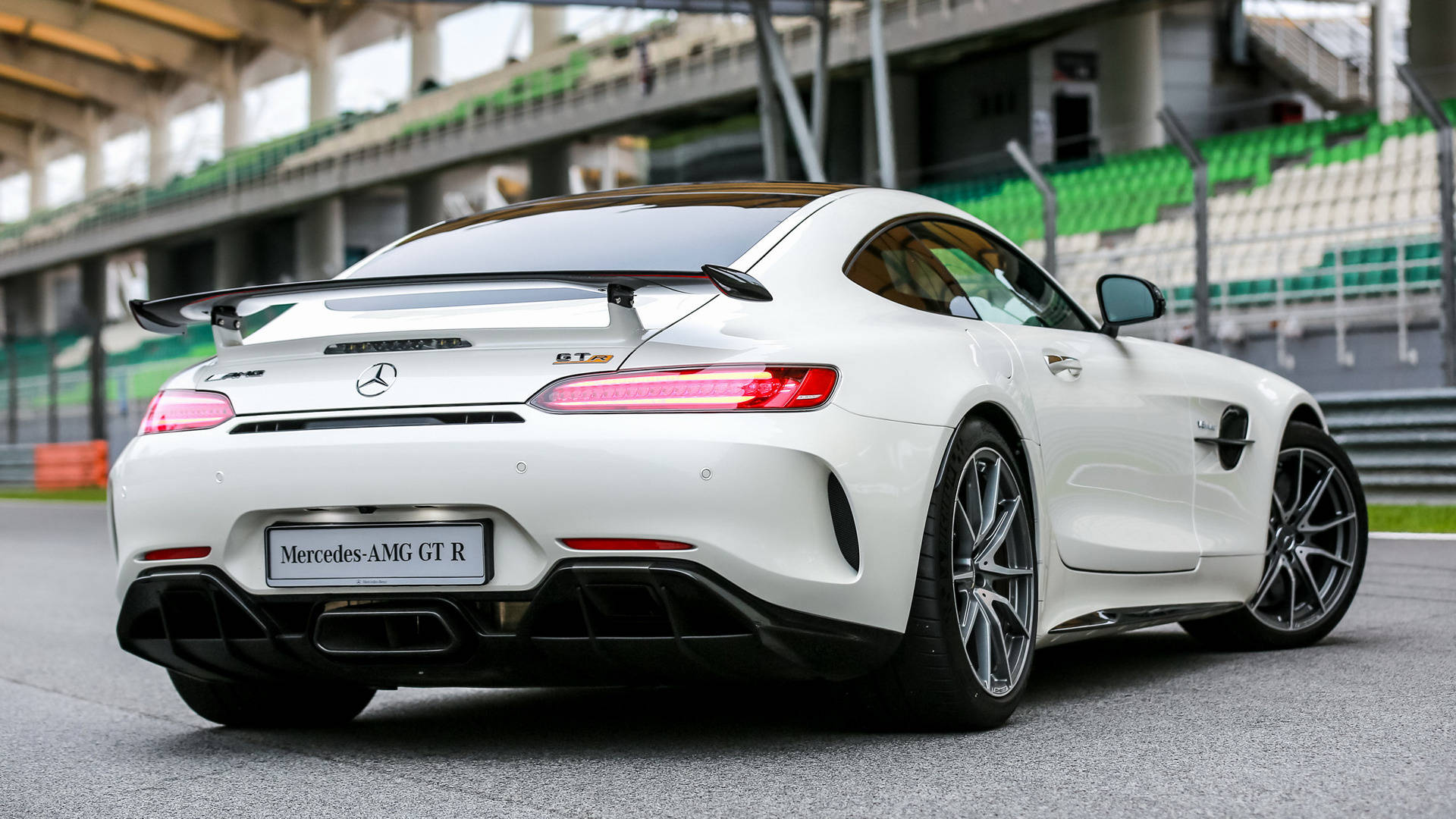 Gtr 桌布 壁紙 — 一輛純白色的 Mercedes-AMG GT R 跑車停在賽車場上，背景是綠色和白色的看台。