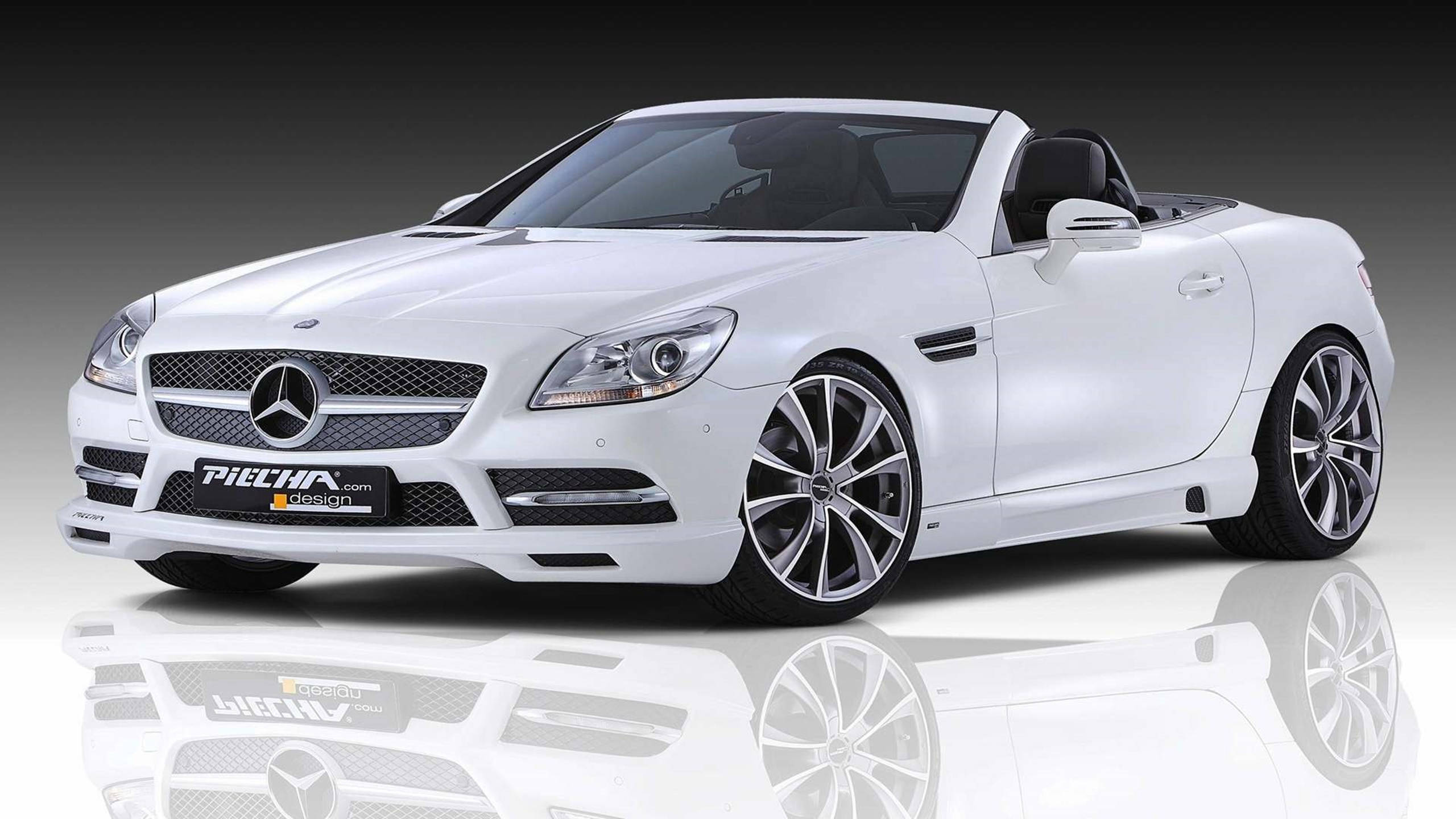 高清 桌布 壁紙 — 一輛純白色的 Mercedes-Benz SLK 敞篷跑車，配備客製化的 Piecha Design 輪圈，在深色漸層背景的反射工作室地板上展示。