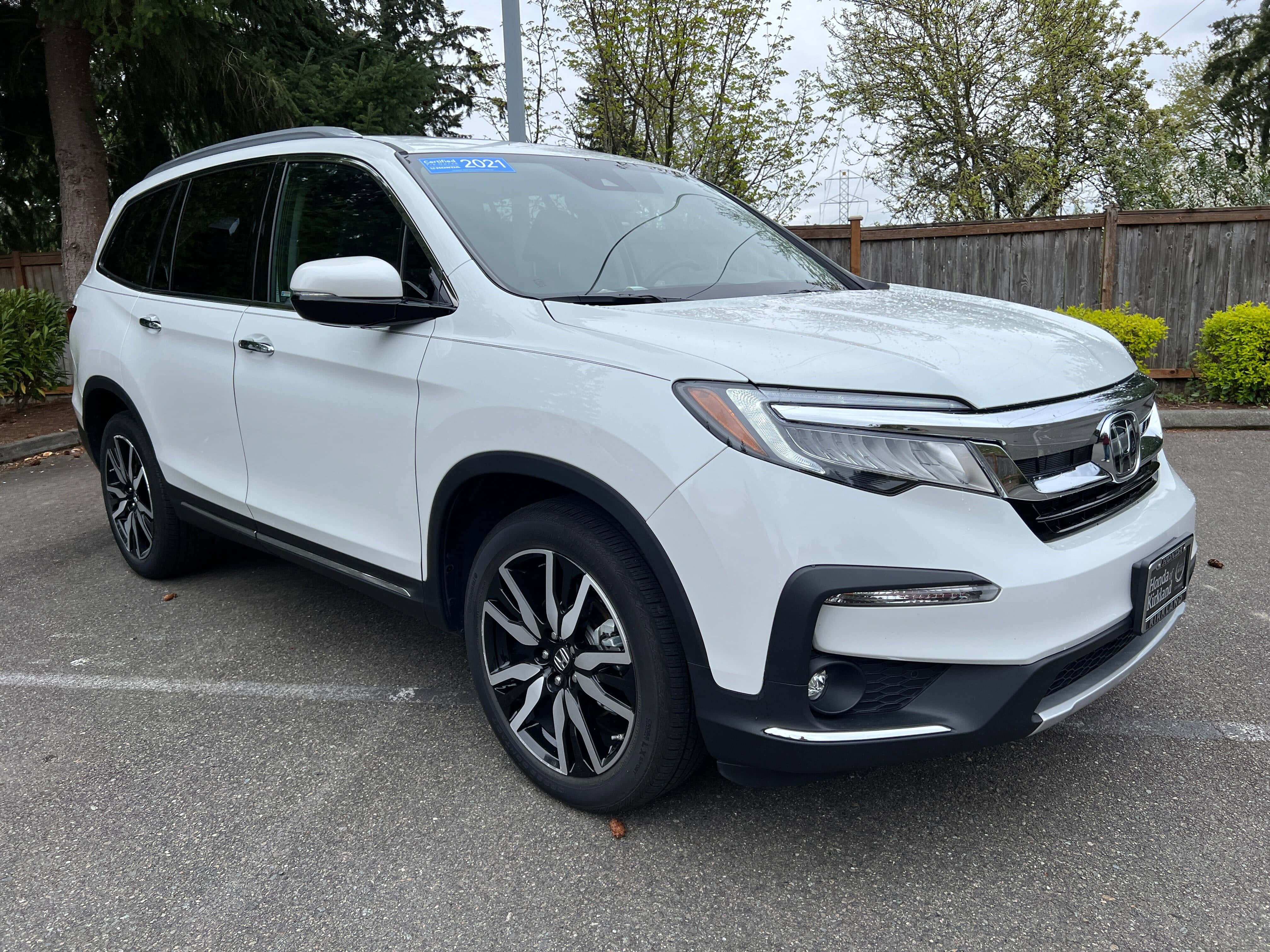 Honda Pilot 桌布 壁紙 — 一輛純白色的2021年本田Pilot SUV停放在瀝青停車場，背景有樹木和木柵欄。