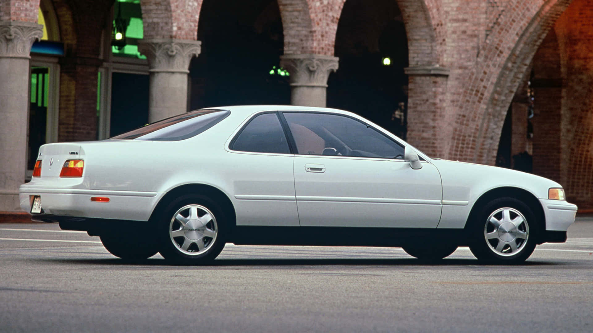 Acura Legend 桌布 壁紙 — 一輛純白色的Acura NSX雙門跑車停放在磚拱門下，搭配古典柱廊，位於陽光明媚的城市廣場。