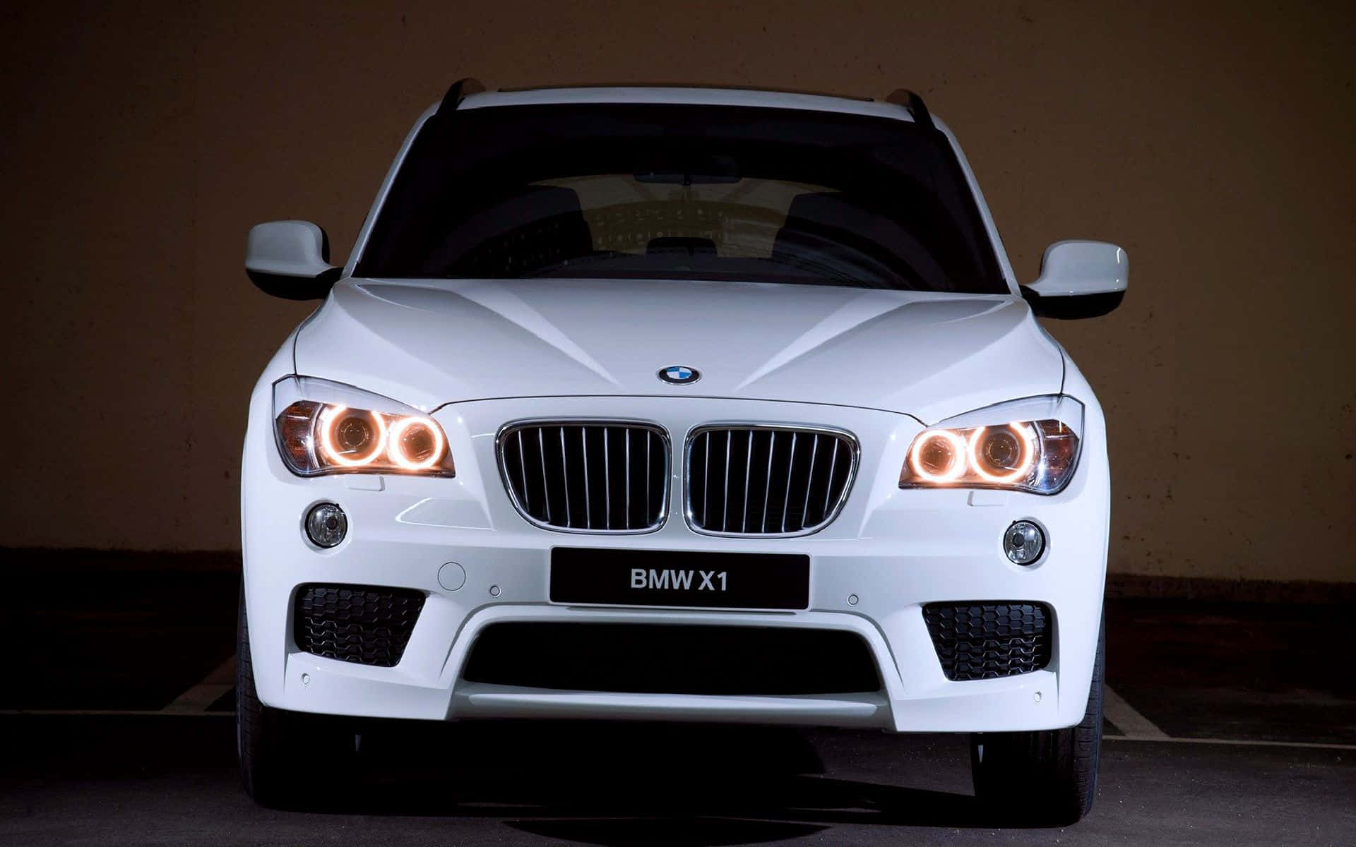 Bmw X1 桌布 壁紙 — 一輛純白色的BMW X1 SUV正面朝前，發光的環形頭燈映襯著黑暗的隧道牆壁。