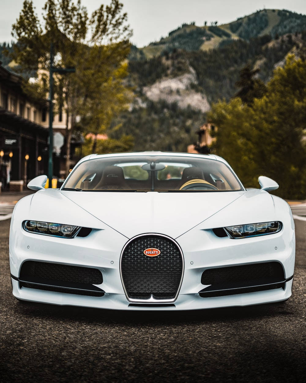 Cool Bugatti 桌布 壁紙 — 一輛純白色的Bugatti Chiron停泊在街道上，背景是山脈和樹木。