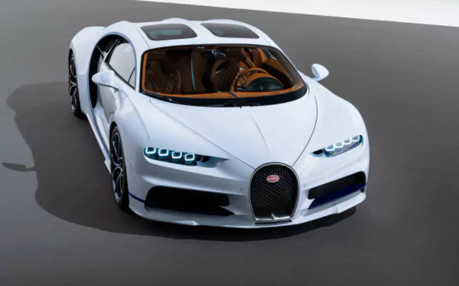 4K 桌布 壁紙 — 一輛純白色的Bugatti Chiron跑車，帶有發光的藍色頭燈和橙色內飾，停在簡約的灰色工作室地板上。