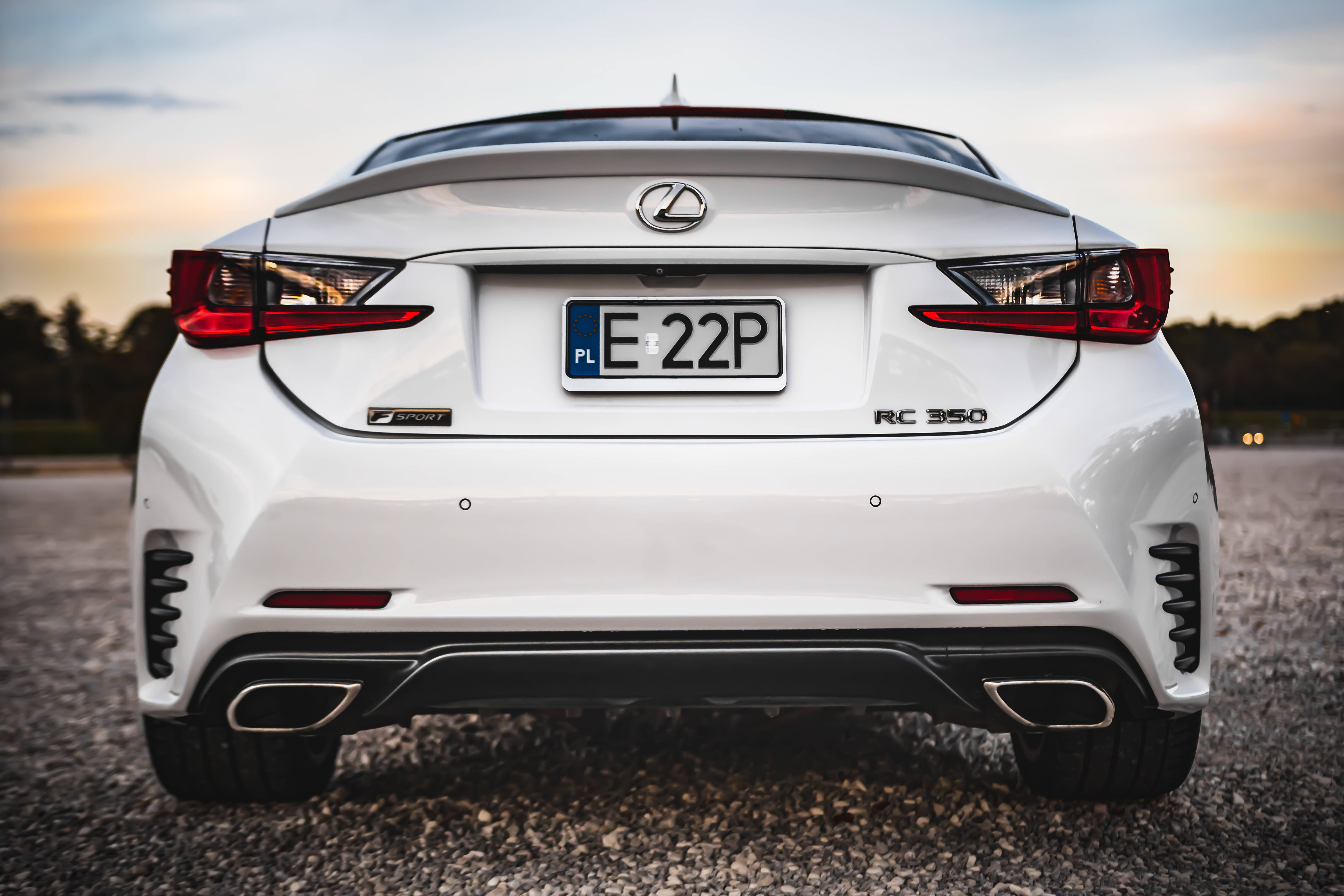 lexus iPhone 桌布 壁紙 — 一輛純白色的Lexus RC 350 F Sport在日落時分停在碎石路上，天空色調溫暖。
