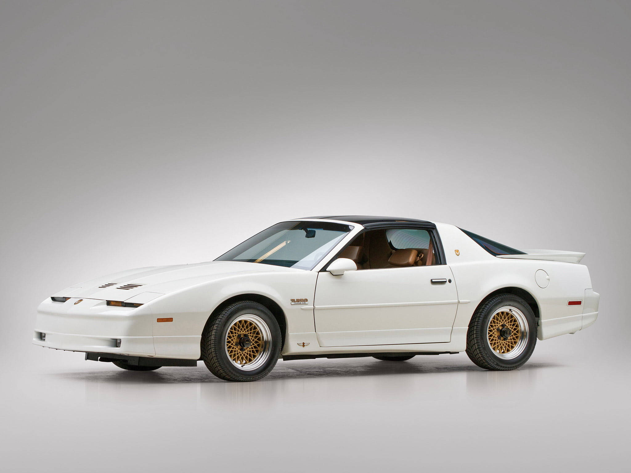 龐蒂克 桌布 壁紙 — 一輛純白色的Pontiac Fiero Turbo搭配金色輪圈，在極簡風格的攝影棚中展示其80年代跑車的流線設計。