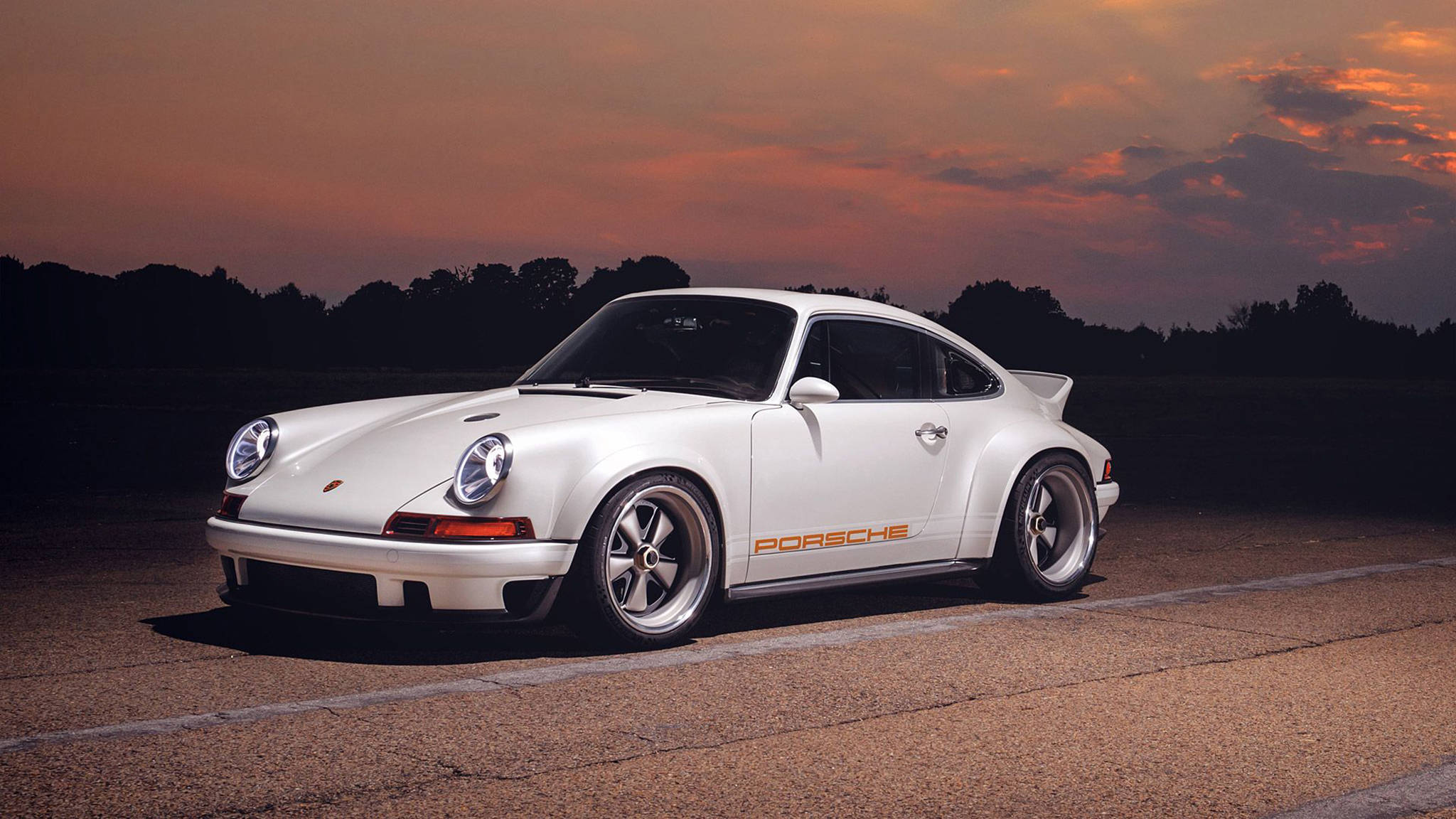 Singer 桌布 壁紙 — 一輛純白色的保時捷911經典跑車停泊在柏油路上，背景是熾熱的日落天空。