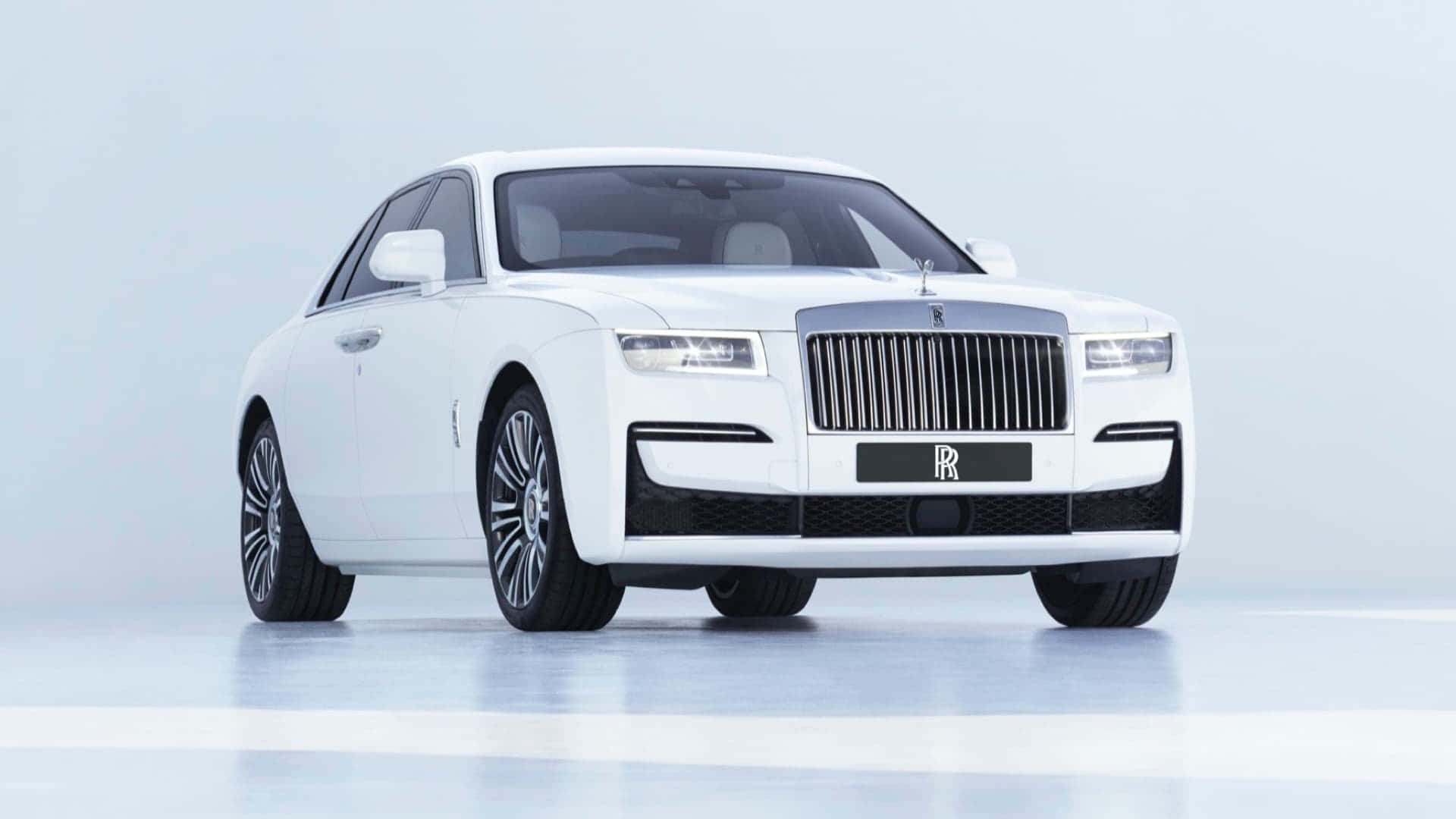 汽車 桌布 壁紙 — 一輛純白色的勞斯萊斯 Ghost 在柔和的工作室燈光下，以簡約的淺灰色背景襯托，閃閃發光。