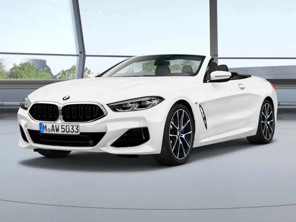 BMW 動圖 桌布 壁紙 — 一輛純白色的寶馬敞篷跑車在明亮的攝影棚燈光下閃閃發光，背景是現代玻璃建築。