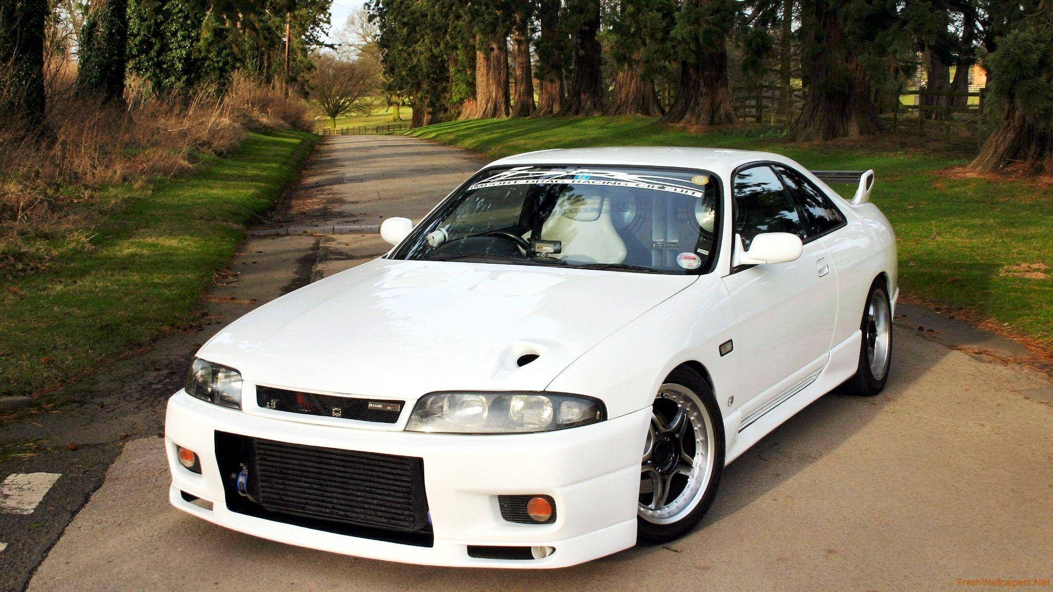 Gtr 桌布 壁紙 — 一輛純白色的日產Skyline R33 GT-R停泊在樹木成蔭的鄉村道路上，沐浴在柔和的白日光線下。