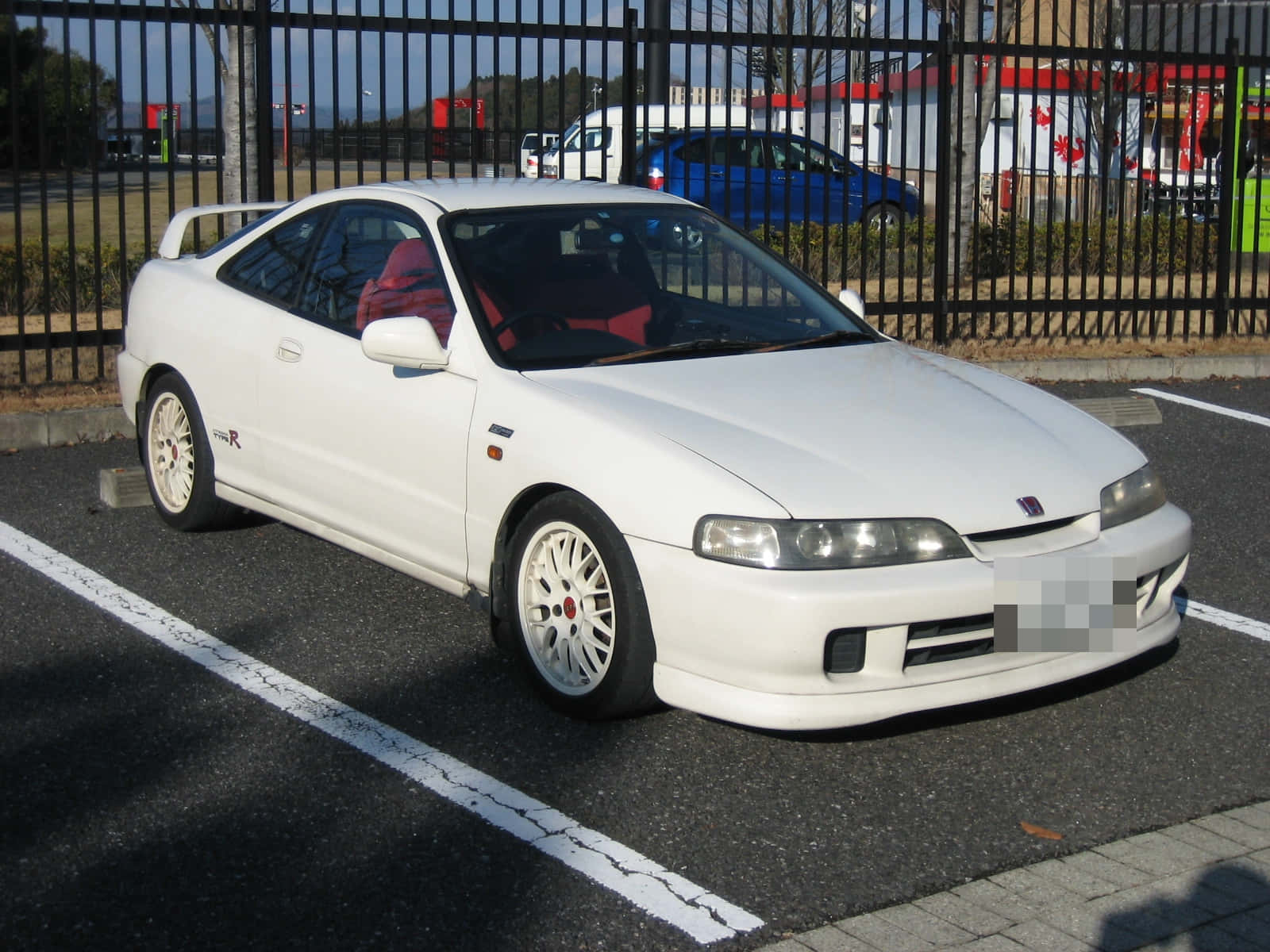 Honda Integra 桌布 壁紙 — 一輛純白色的本田 Integra Type R 雙門跑車停放在陽光明媚的瀝青停車場，紅色內裝透過車窗可見。