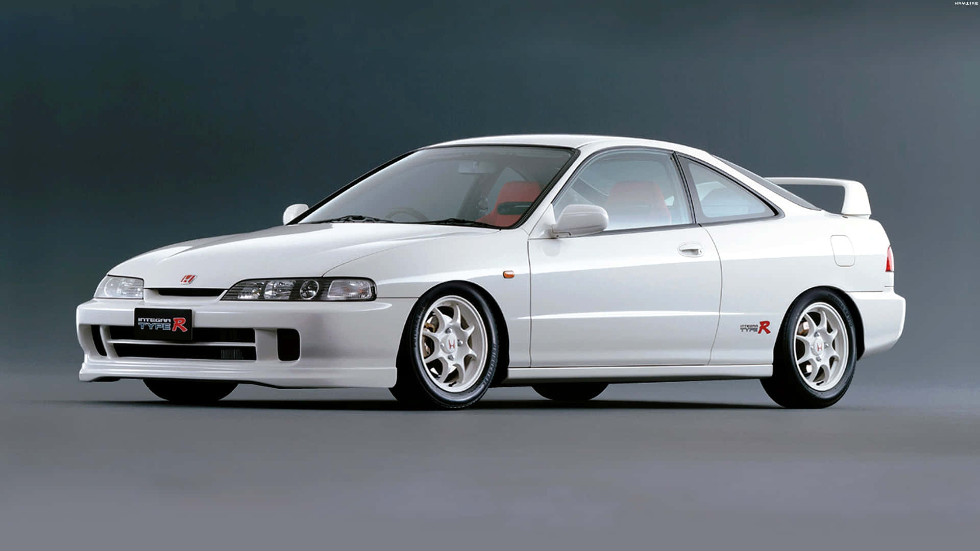 Honda Integra 桌布 壁紙 — 一輛純白色的本田Integra Type R運動轎跑車，配備紅色內裝和改裝輪圈，在深灰色工作室背景前展示。